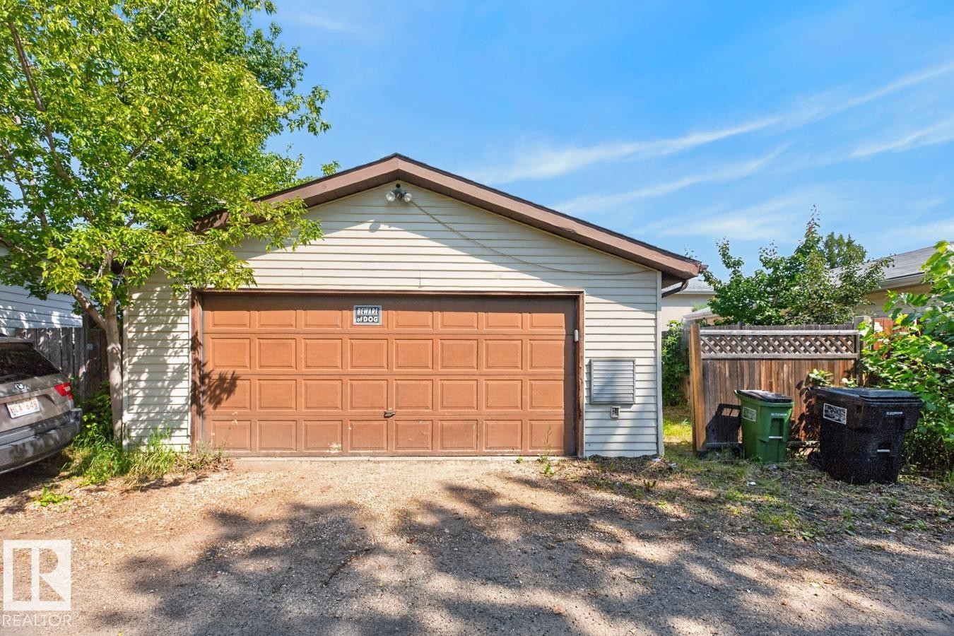 Detached garage with a paneled brown garage door, light-colored siding, and a brown trim roofline - 4003 41 Avenue Nw, Edmonton, AB - Outdoor With Exterior