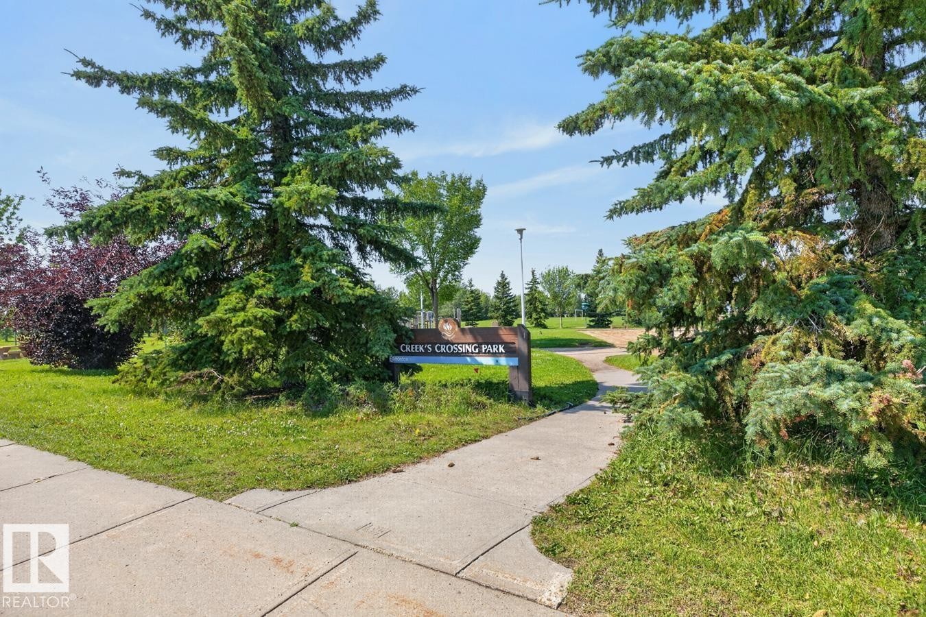Landscaped park entrance featuring mature evergreen trees and a paved pathway - 4003 41 Avenue Nw, Edmonton, AB - Outdoor