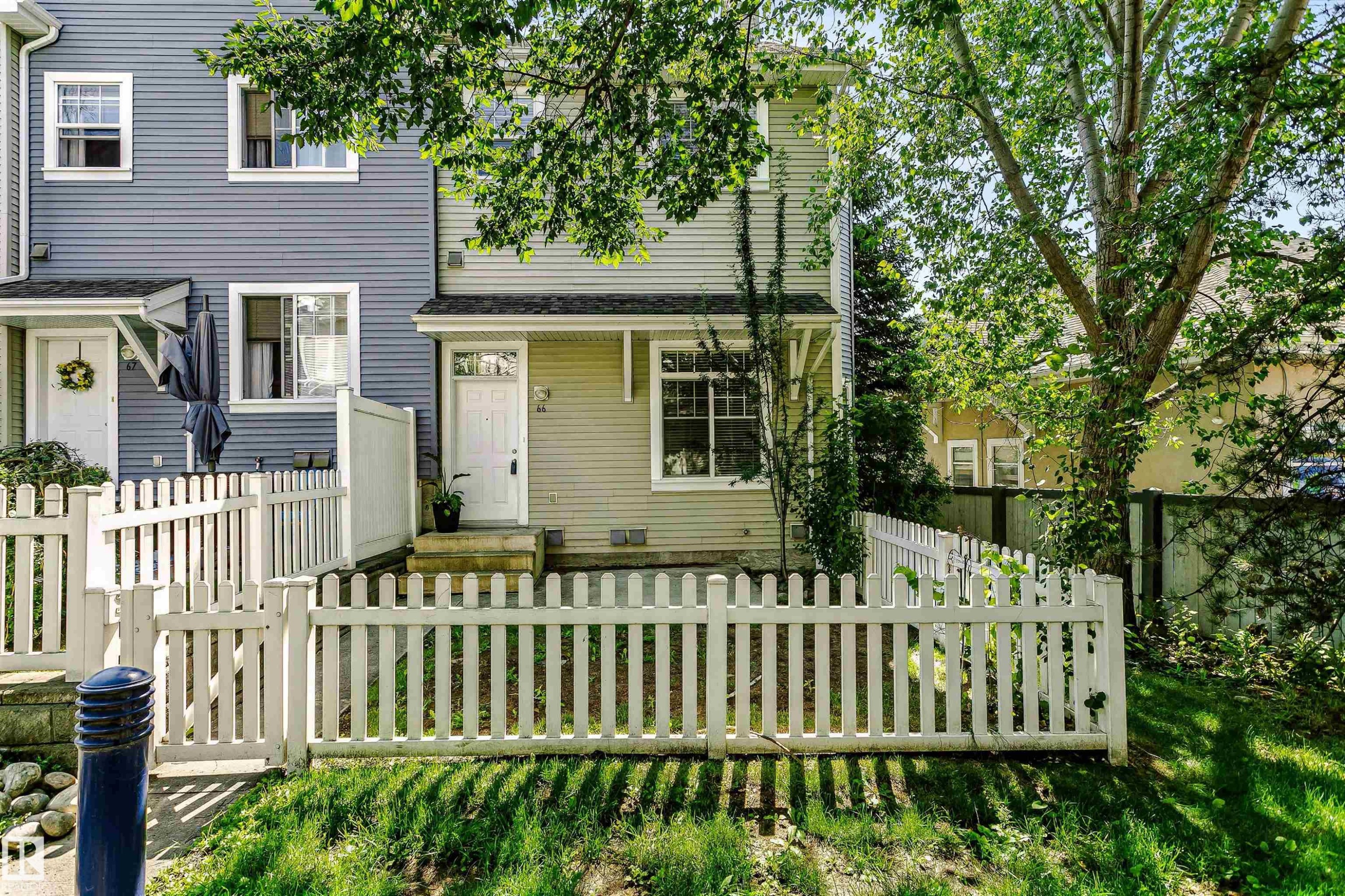 Exterior featuring light green horizontal siding and a white picket fence - #66 8304 11 Av Sw, Edmonton, AB - Outdoor