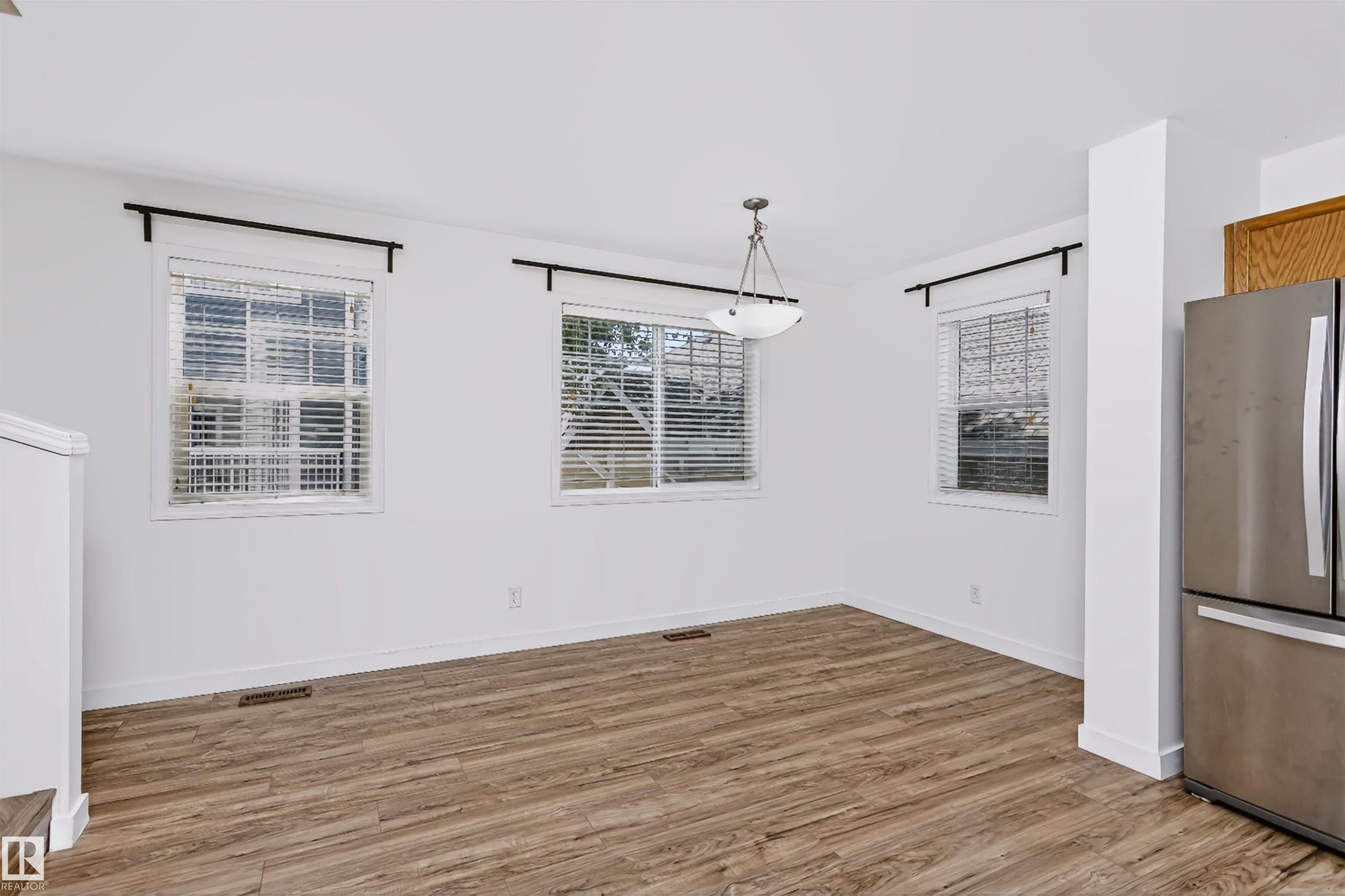 Dining space featuring wood-finish flooring, white walls, and a contemporary semi-flush mount light fixture - #66 8304 11 Av Sw, Edmonton, AB - Indoor Photo Showing Other Room