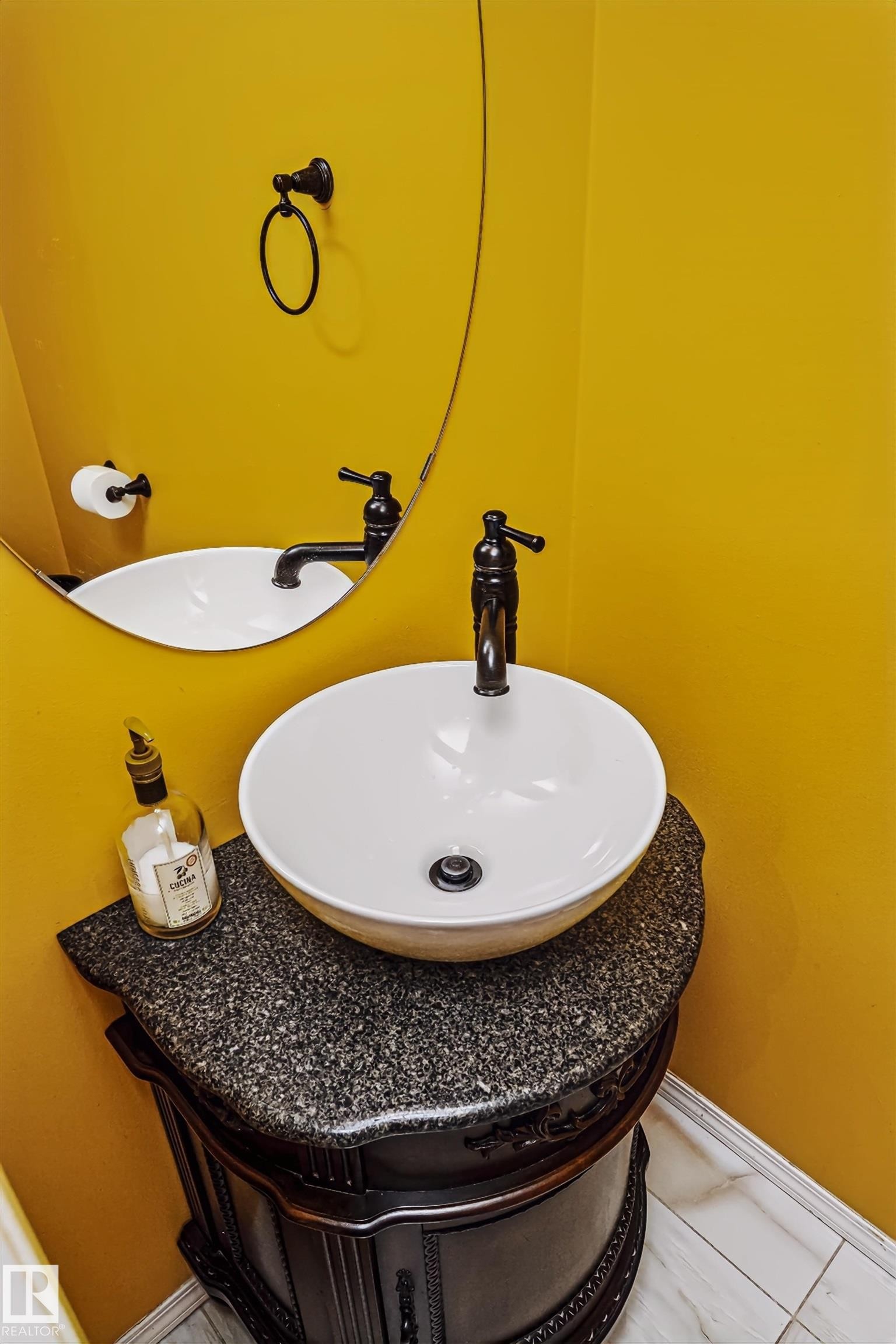 Vanity with a vessel sink, dark granite countertop, and ornate wood-finish cabinetry - #66 8304 11 Av Sw, Edmonton, AB - Indoor Photo Showing Bathroom