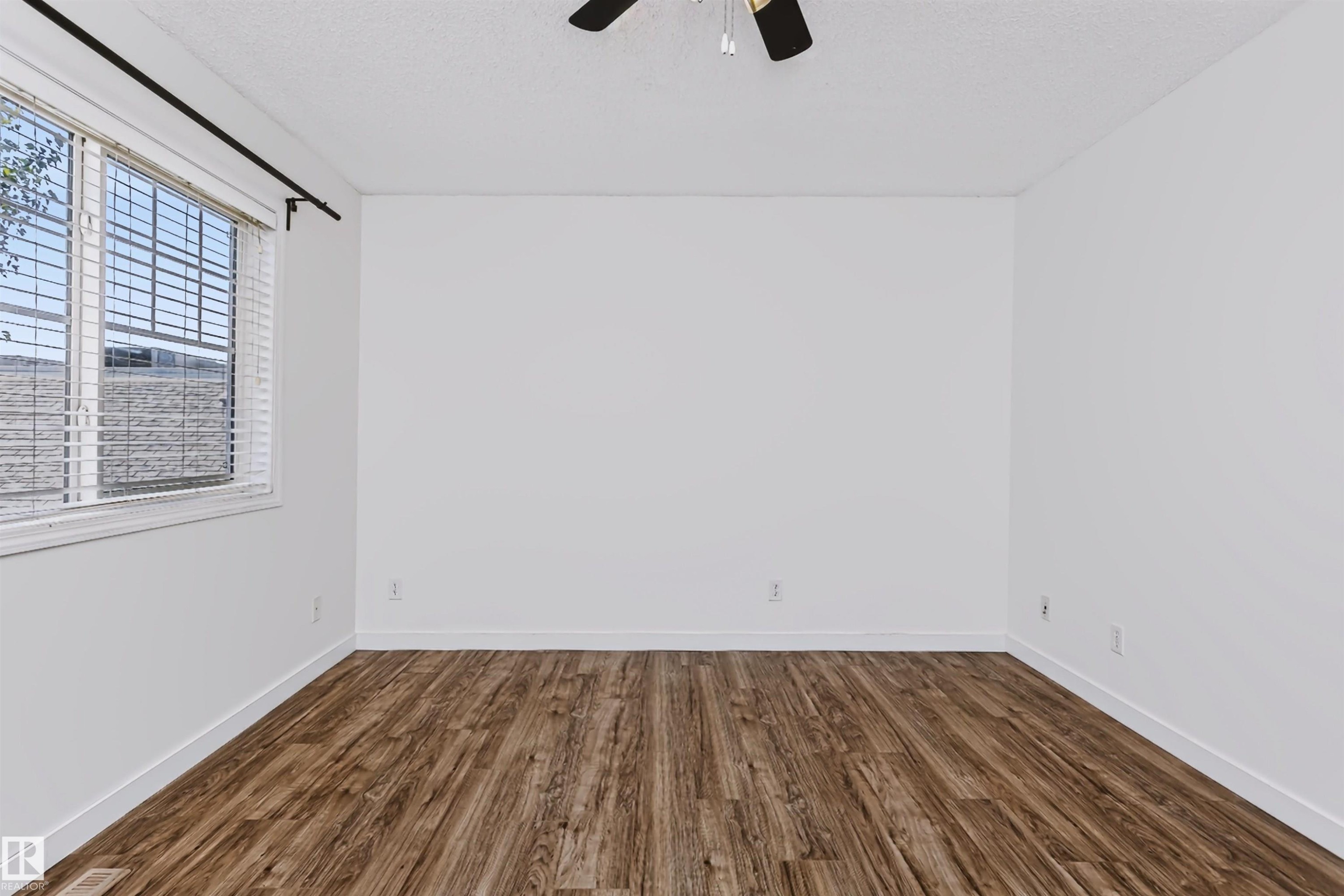 Spacious room featuring wood-finish flooring and a ceiling fan - #66 8304 11 Av Sw, Edmonton, AB - Indoor Photo Showing Other Room