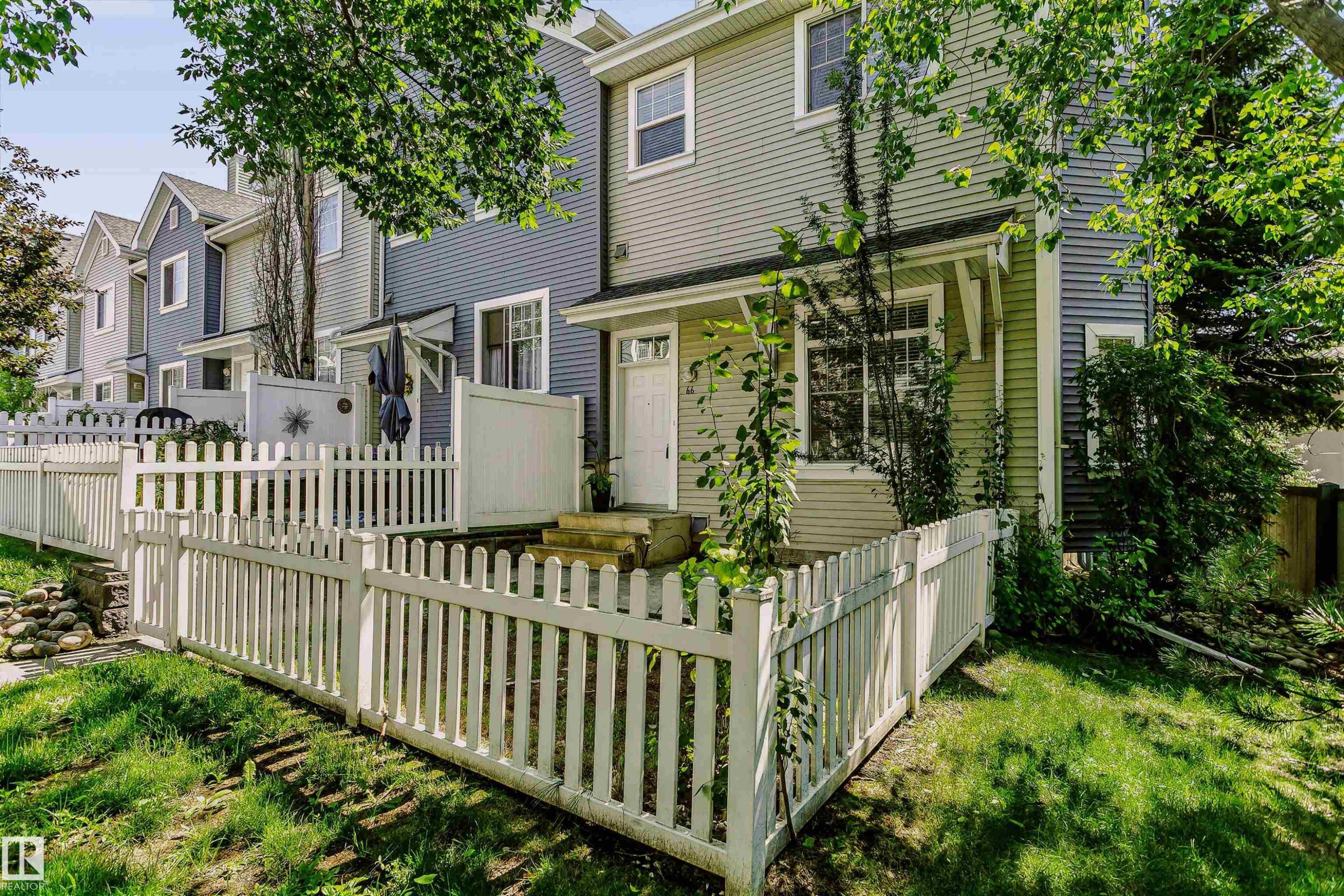 Charming townhome exterior featuring light green and blue-grey siding - #66 8304 11 Av Sw, Edmonton, AB - Outdoor