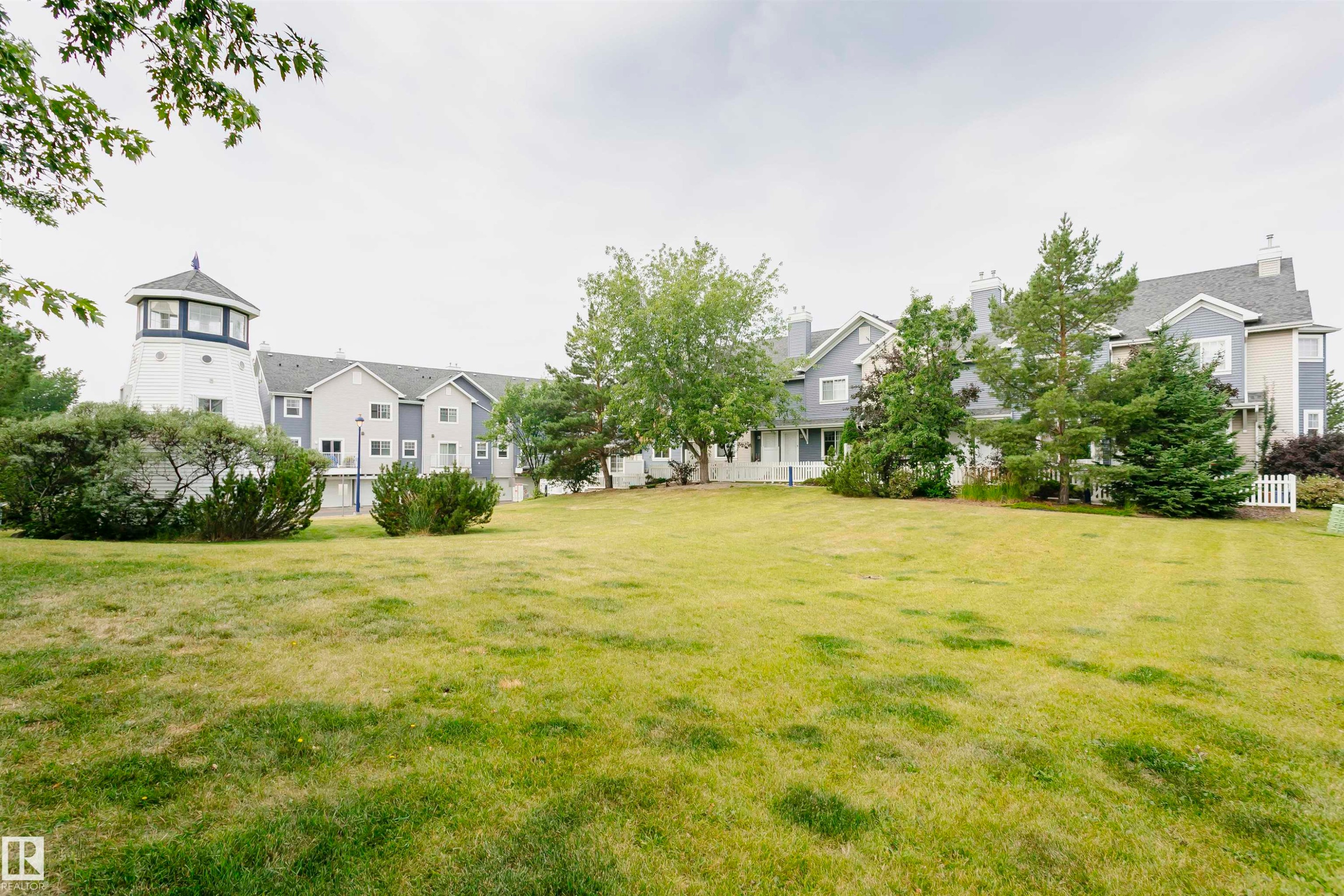 Large green lawn with scattered trees and shrubs - #66 8304 11 Av Sw, Edmonton, AB - Outdoor
