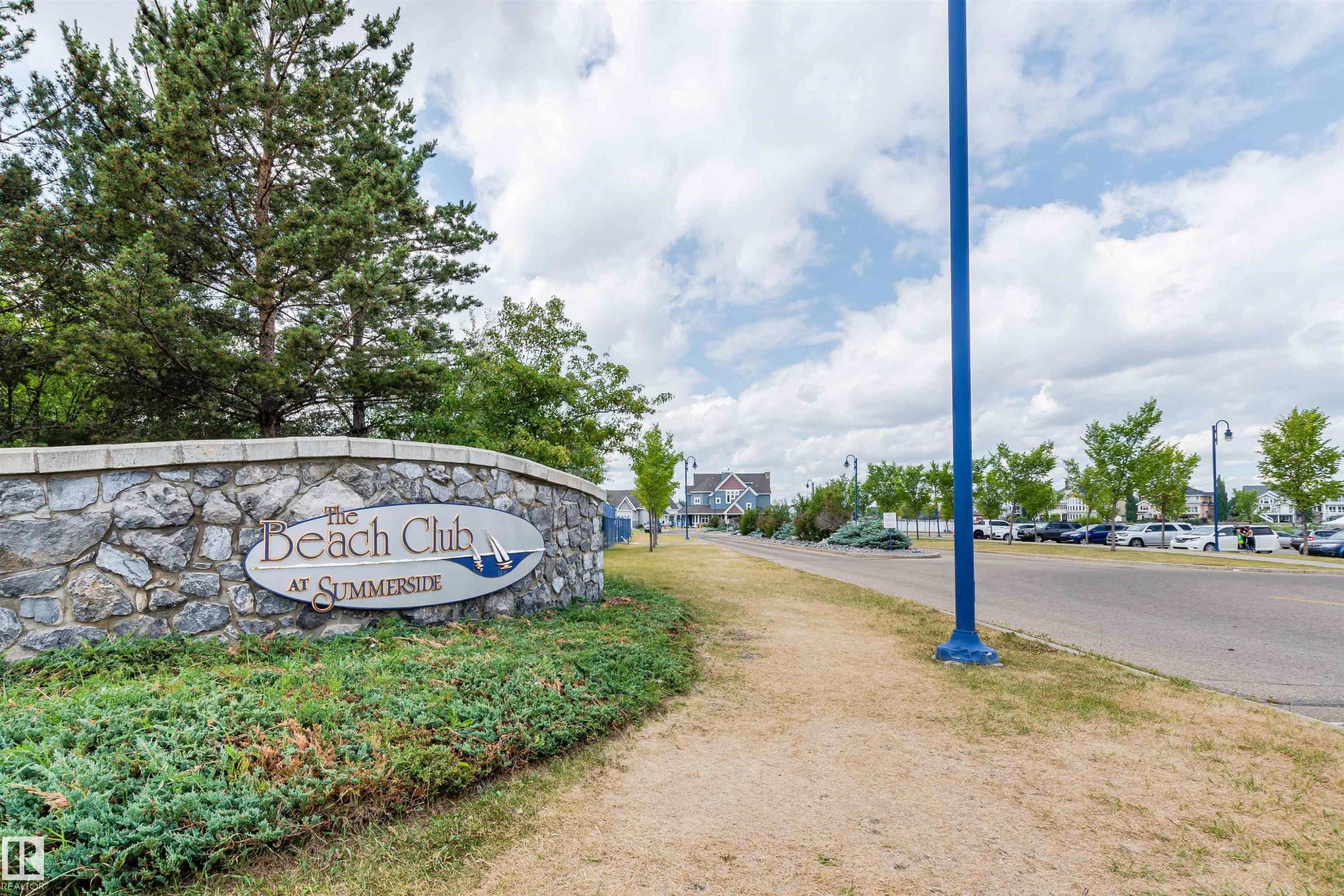 Stone wall signage for "The Beach Club at Summerside" with mature landscaping - #66 8304 11 Av Sw, Edmonton, AB - Outdoor With View