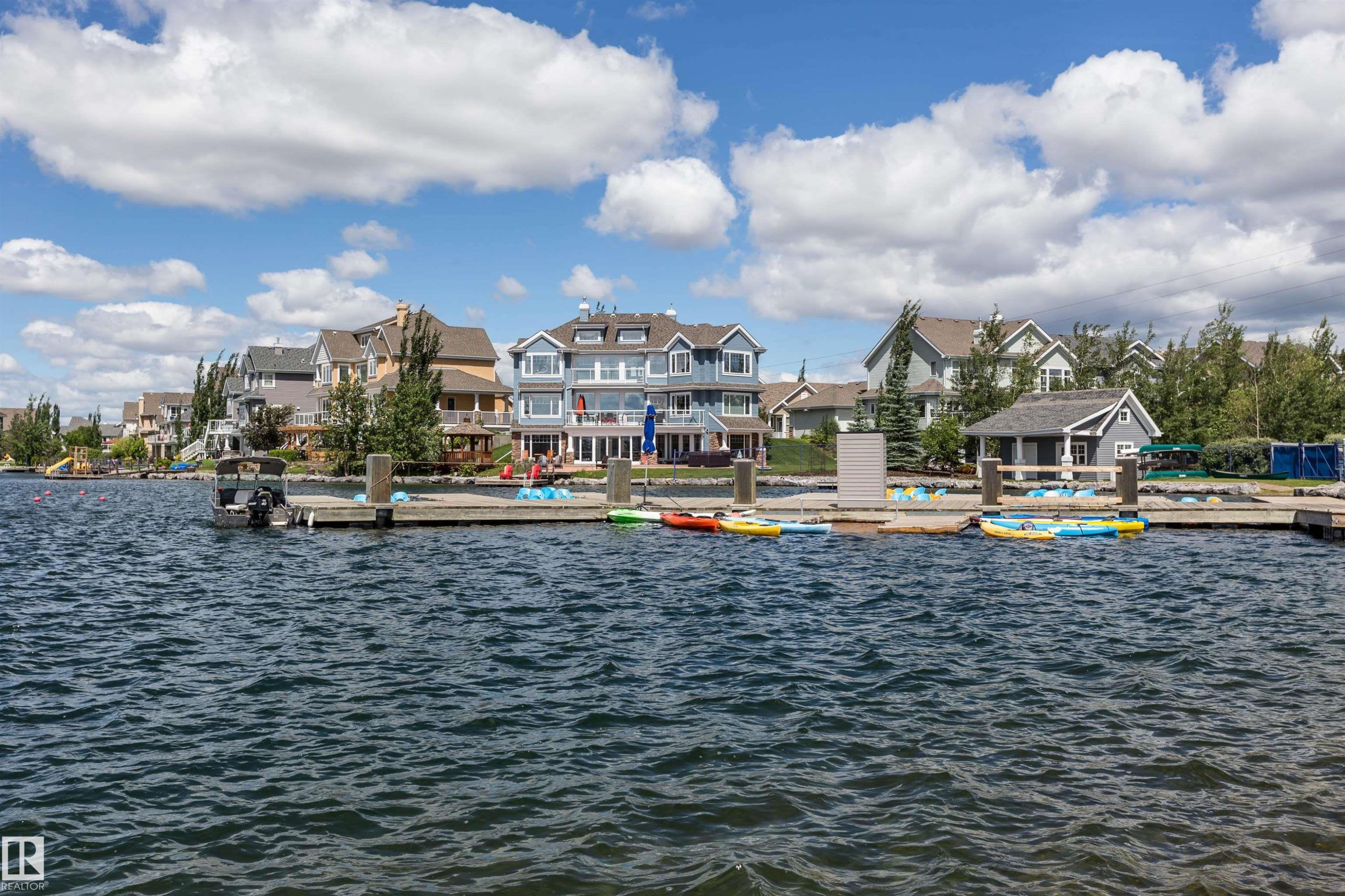 Waterfront property featuring an expansive private dock with multiple berthing stations, a spacious upper deck, and a detached waterside boathouse - #66 8304 11 Av Sw, Edmonton, AB - Outdoor With Body Of Water With View
