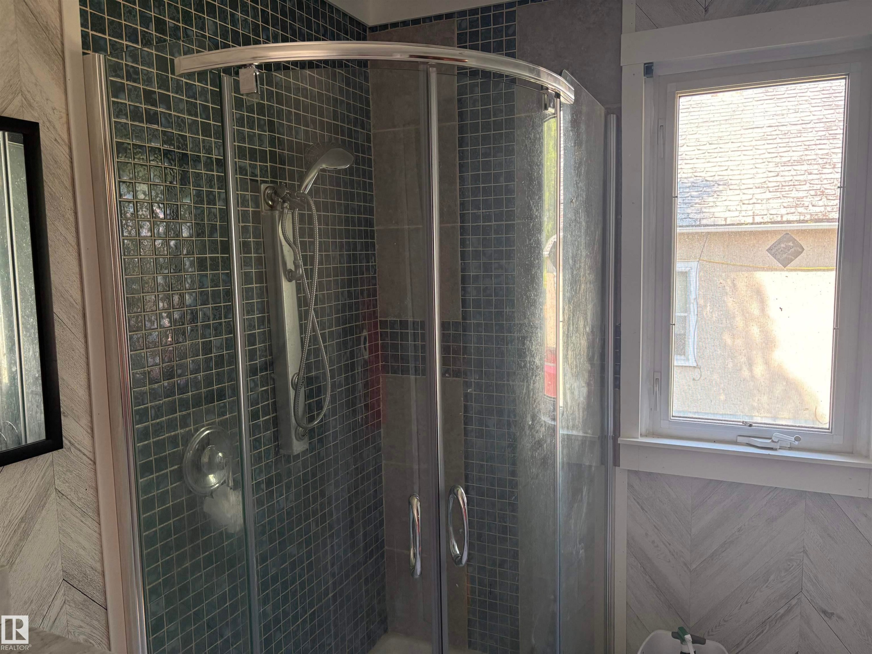 Shower enclosure featuring a curved glass door and dark square mosaic tile - 4620 Maria Drive, Smoky Lake Town, AB - Indoor Photo Showing Bathroom