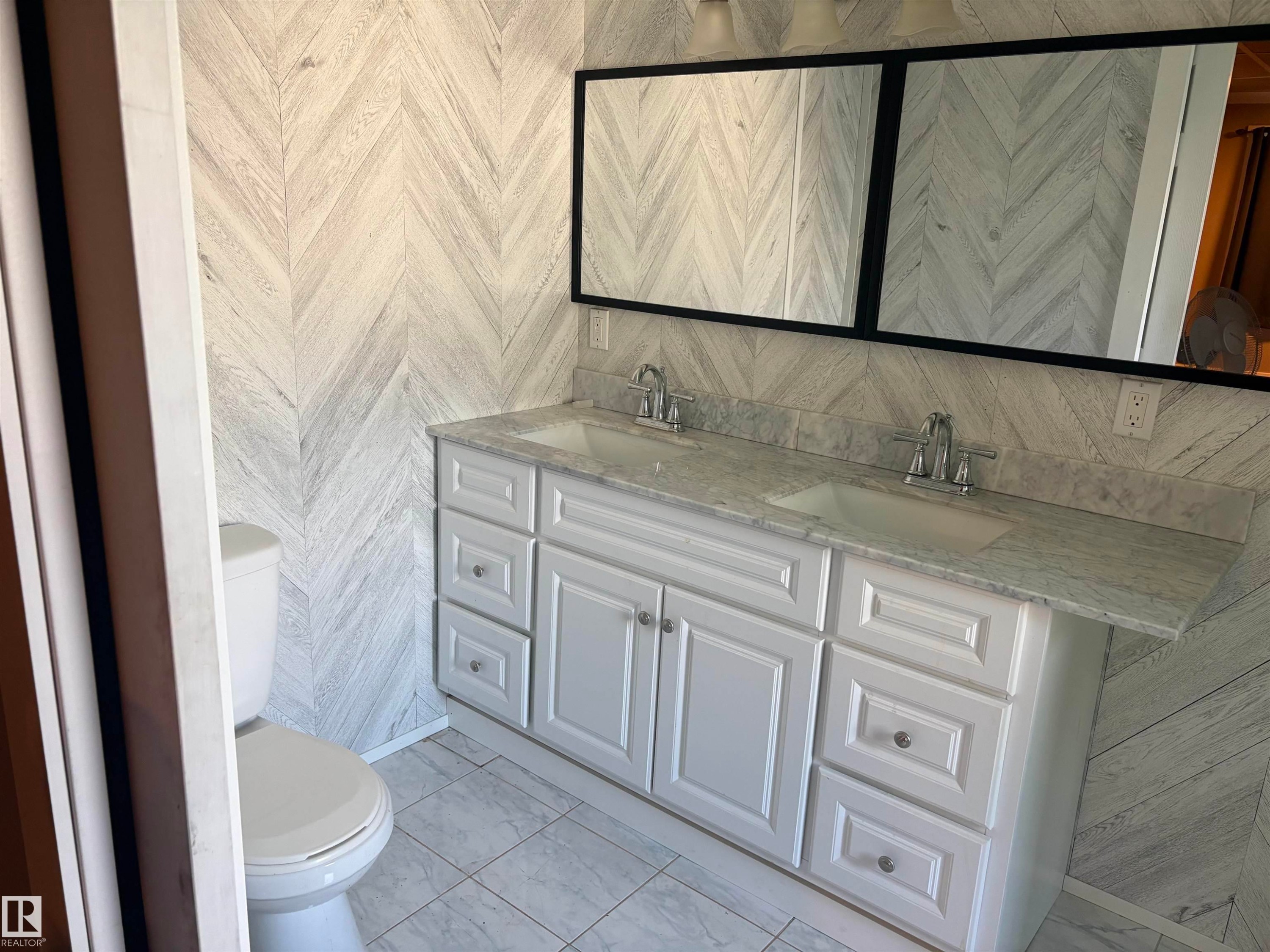 Bathroom featuring a dual vanity with white cabinetry and chrome hardware, a light-toned countertop, and two framed mirrors - 4620 Maria Drive, Smoky Lake Town, AB - Indoor Photo Showing Bathroom