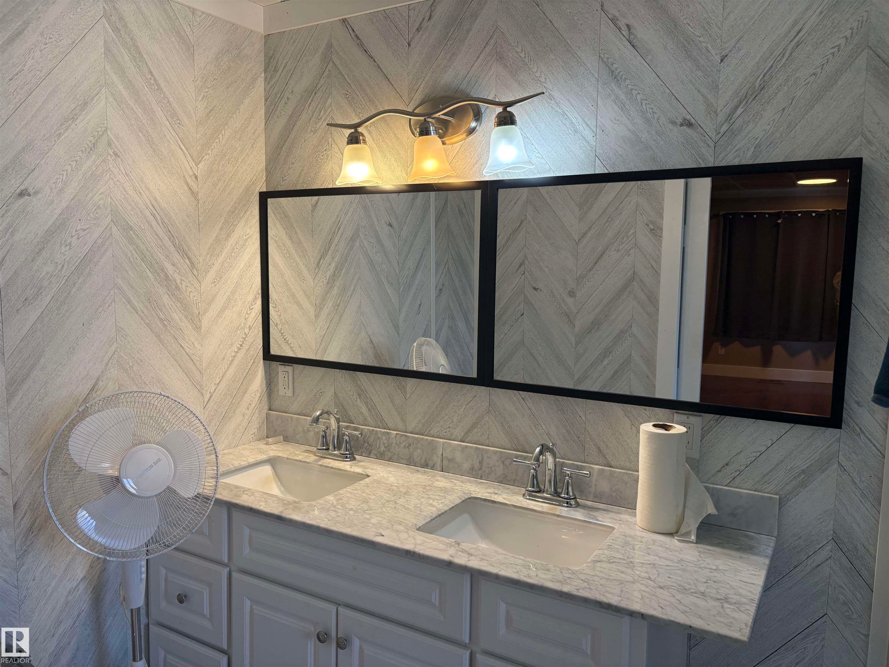 Dual sink vanity with light gray cabinetry, a stone-finish countertop, and chrome fixtures - 4620 Maria Drive, Smoky Lake Town, AB - Indoor Photo Showing Bathroom