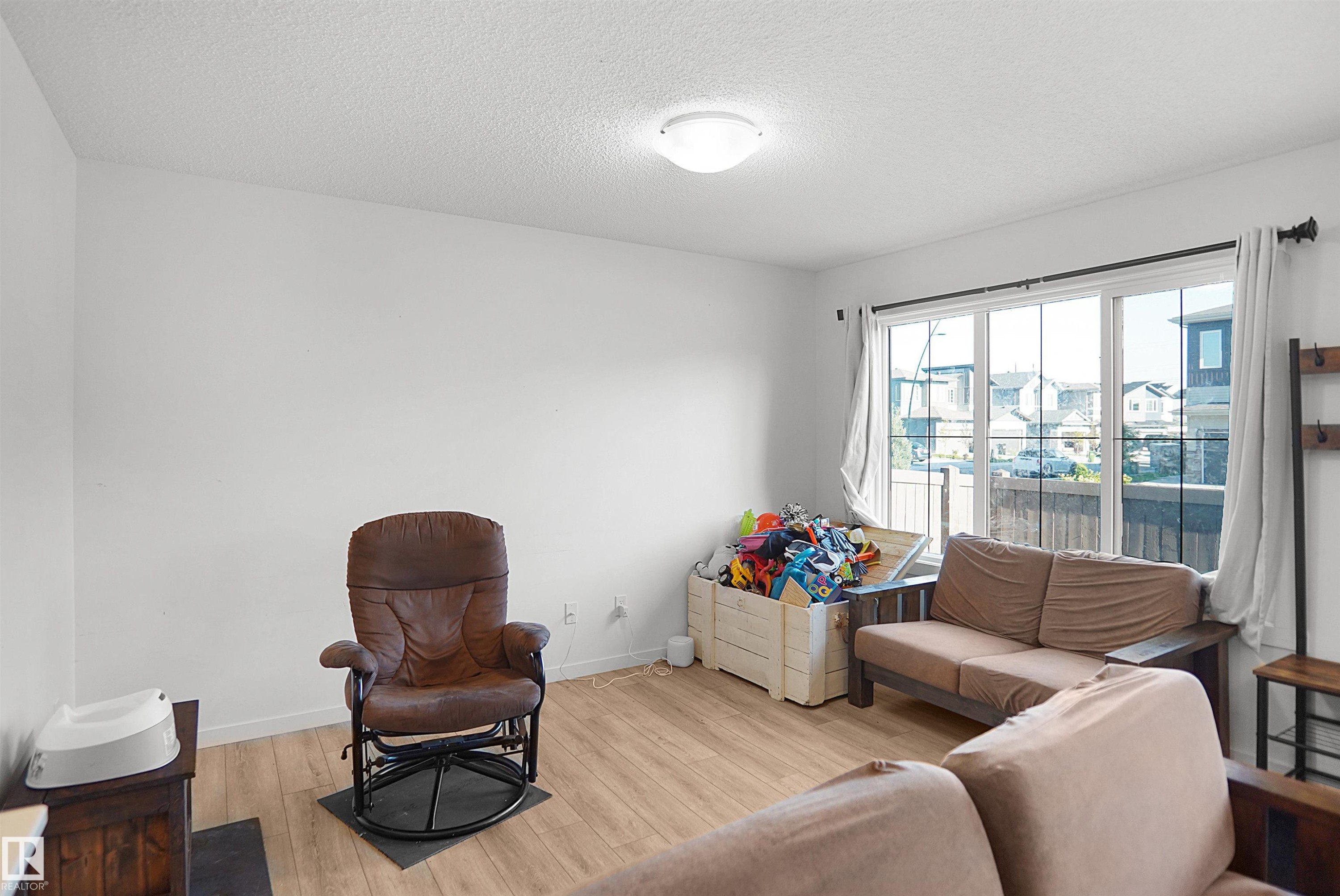 Bright living space featuring expansive windows, wood-finish flooring, and a flush-mount ceiling light fixture - #42 19904 31 Av Nw, Edmonton, AB - Indoor Photo Showing Living Room