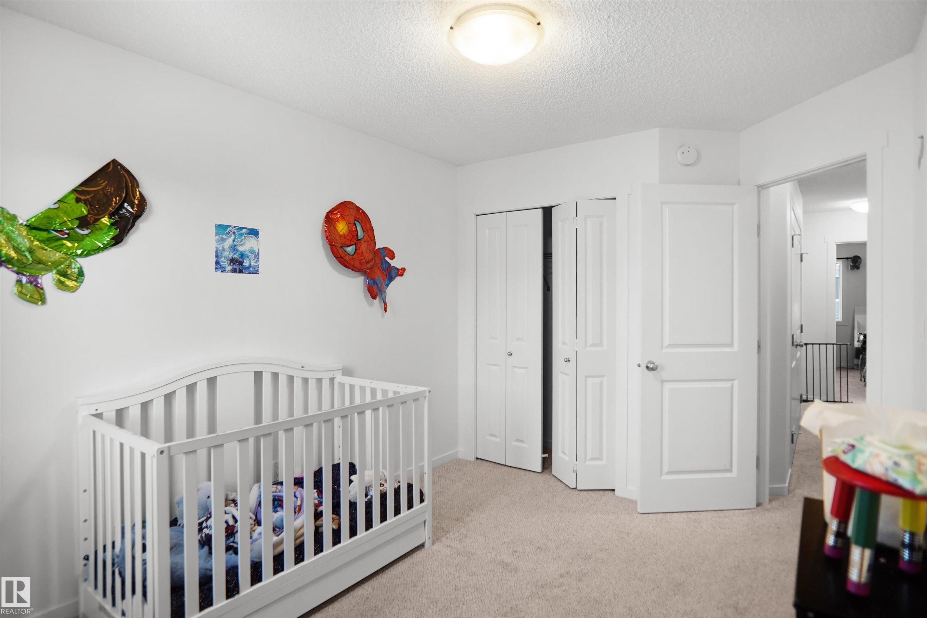 Carpeted room featuring white walls, a flush-mount ceiling light, white bi-fold closet doors, and a paneled entry door - #42 19904 31 Av Nw, Edmonton, AB - Indoor Photo Showing Bedroom