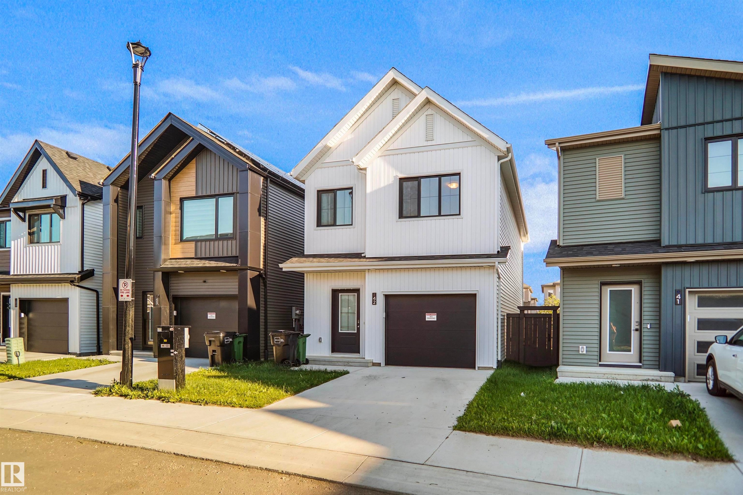 Modern white-sided home featuring a dark brown garage door and matching front door - #42 19904 31 Av Nw, Edmonton, AB - Outdoor With Facade