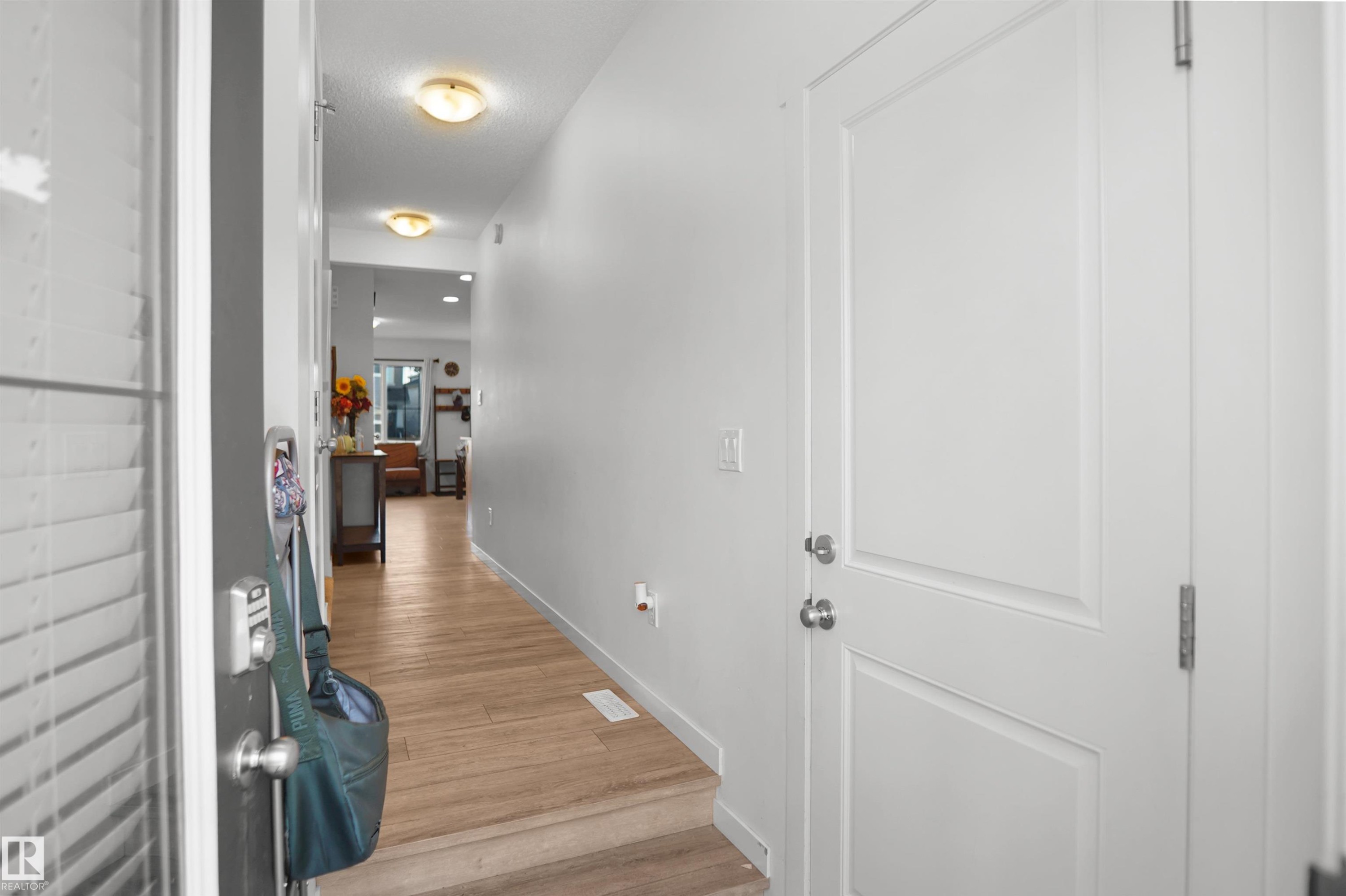 Bright hallway featuring wood-finish flooring, recessed ceiling lights, and light-toned wall paint - #42 19904 31 Av Nw, Edmonton, AB - Indoor Photo Showing Other Room