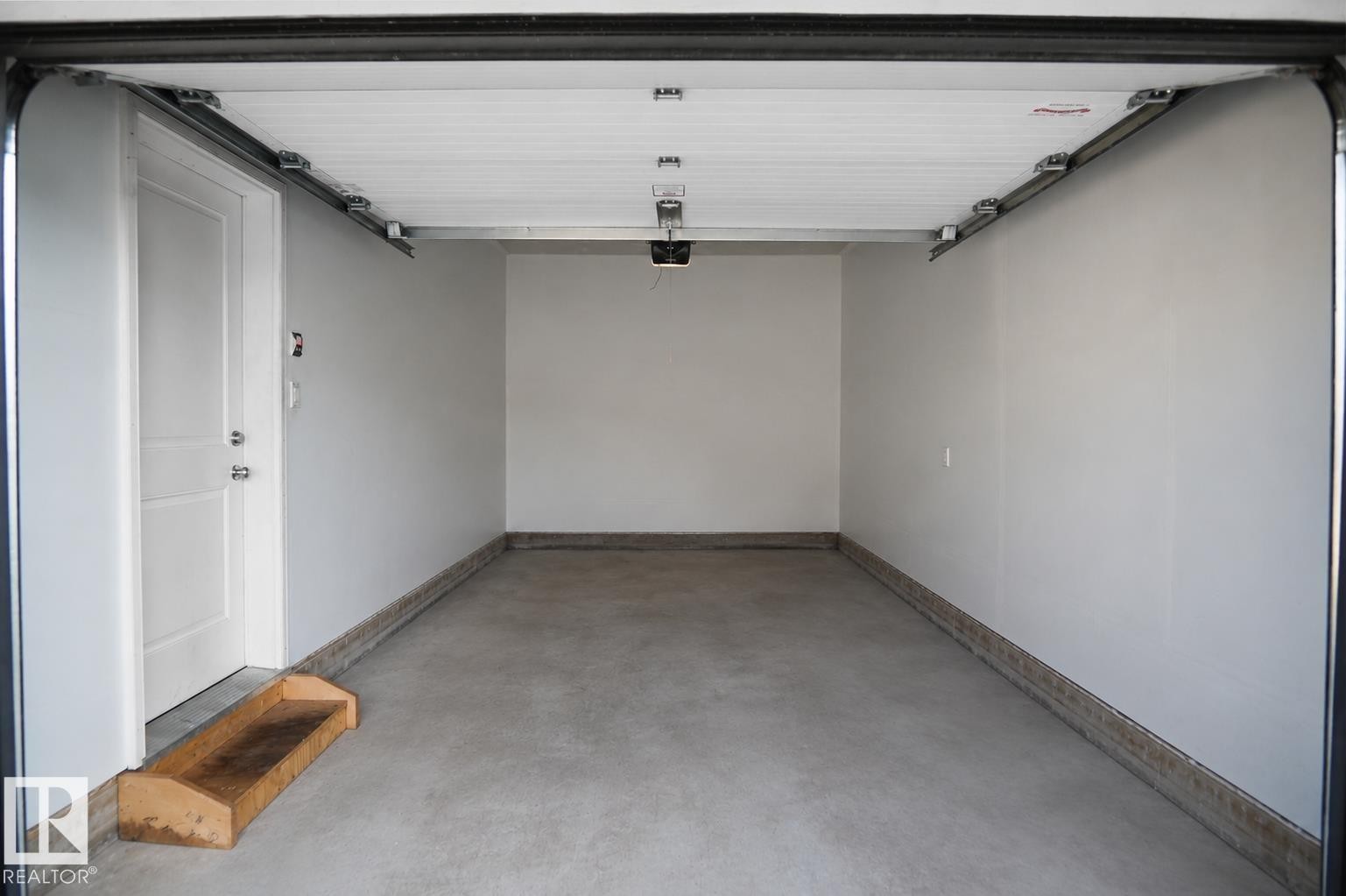 Spacious garage with a concrete floor, white painted walls, and an overhead garage door opener system - #42 19904 31 Av Nw, Edmonton, AB - Indoor Photo Showing Garage