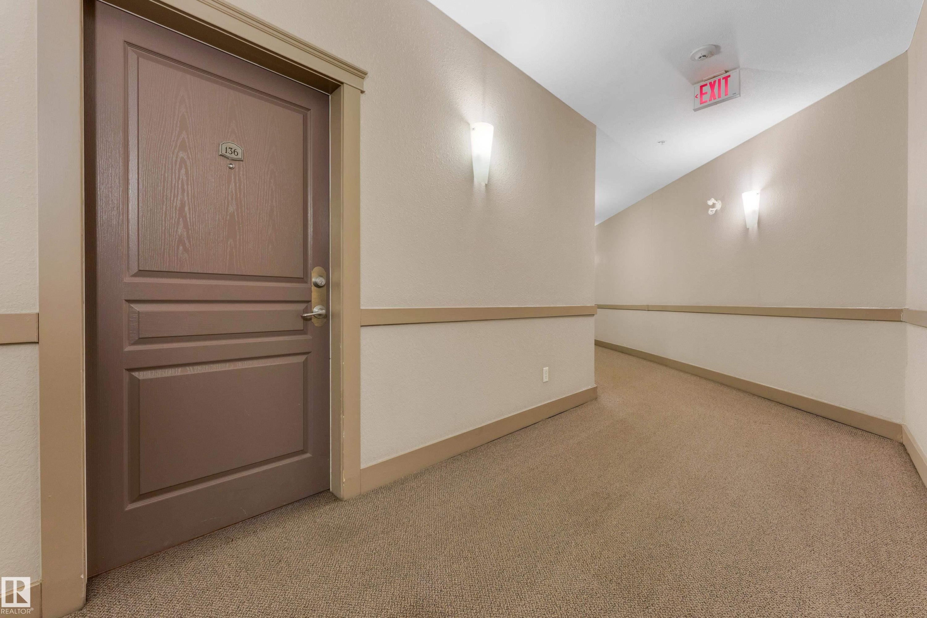 Corridor featuring textured carpeting and neutral paint with chair rail molding - #136 16035 132 St Nw, Edmonton, AB - Indoor Photo Showing Other Room