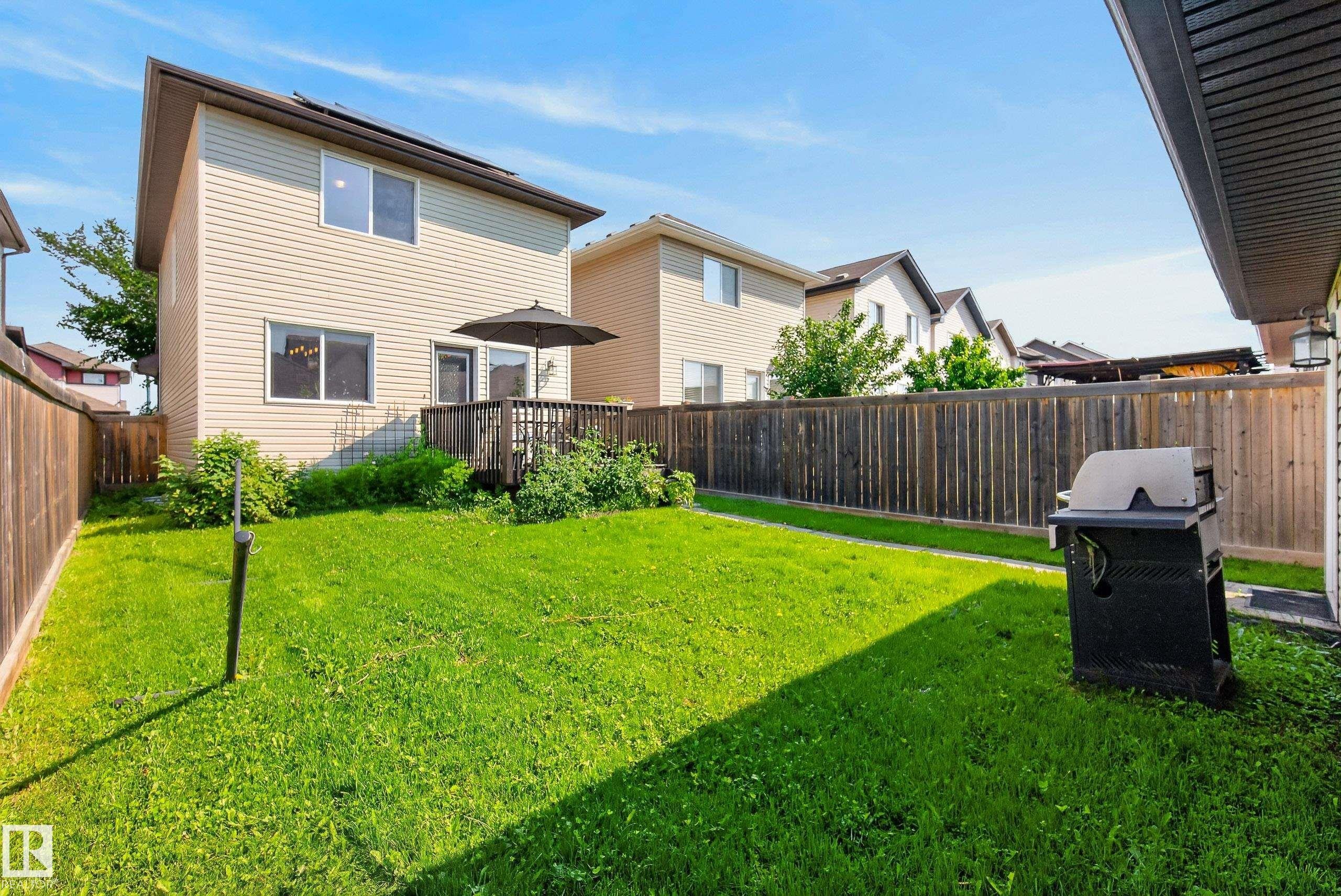 Expansive rear lawn featuring a wooden privacy fence, a raised wooden deck, and vinyl siding on the house exterior - 3003 20 Avenue Nw, Edmonton, AB - Outdoor With Exterior
