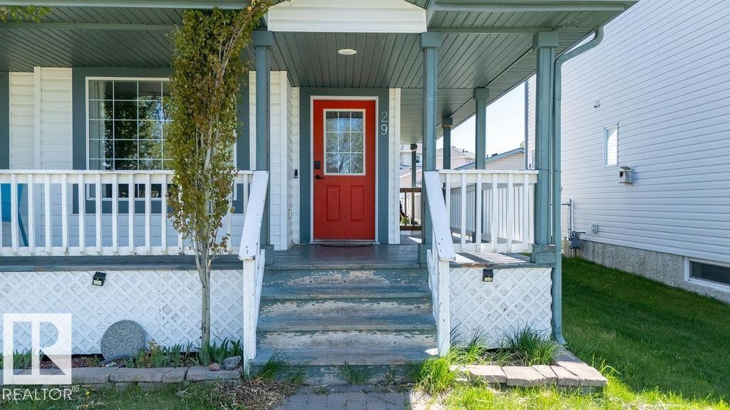 Covered front porch with a vibrant red entry door featuring glass panels - 29 Campbell Road, Leduc, AB - Outdoor