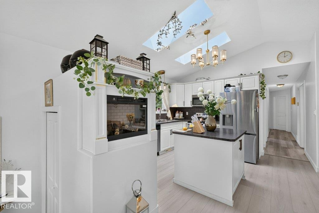 Vaulted ceiling kitchen featuring two skylights and a gold chandelier - 12219 89 Street Nw, Edmonton, AB - Indoor