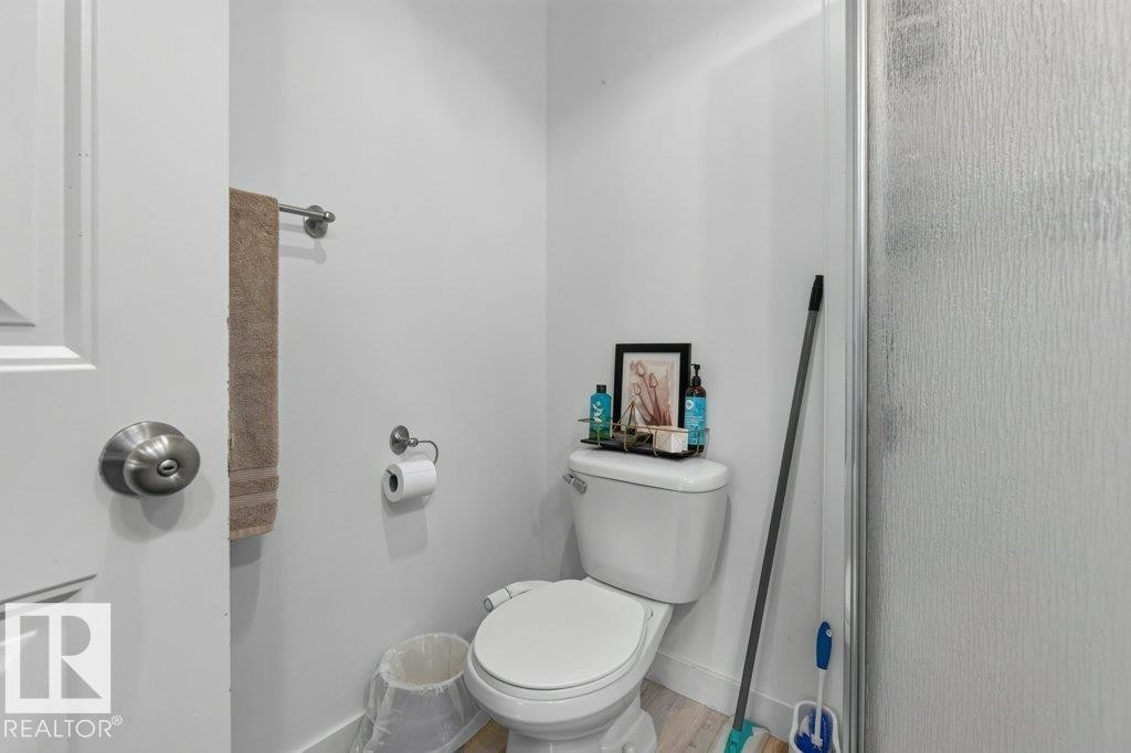 White commode with a ceramic tank and bowl, alongside a textured glass shower enclosure - 12219 89 Street Nw, Edmonton, AB - Indoor Photo Showing Bathroom