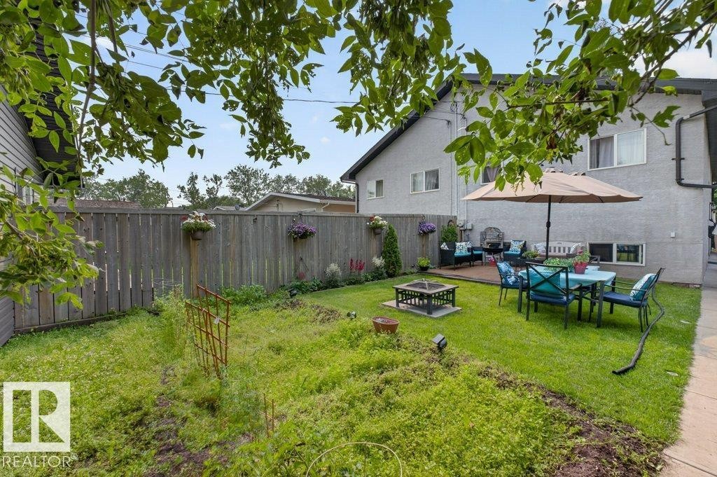 Expansive backyard featuring a partial wood fence, a fire pit area, and a dedicated wooden deck space - 12219 89 Street Nw, Edmonton, AB - Outdoor With Backyard