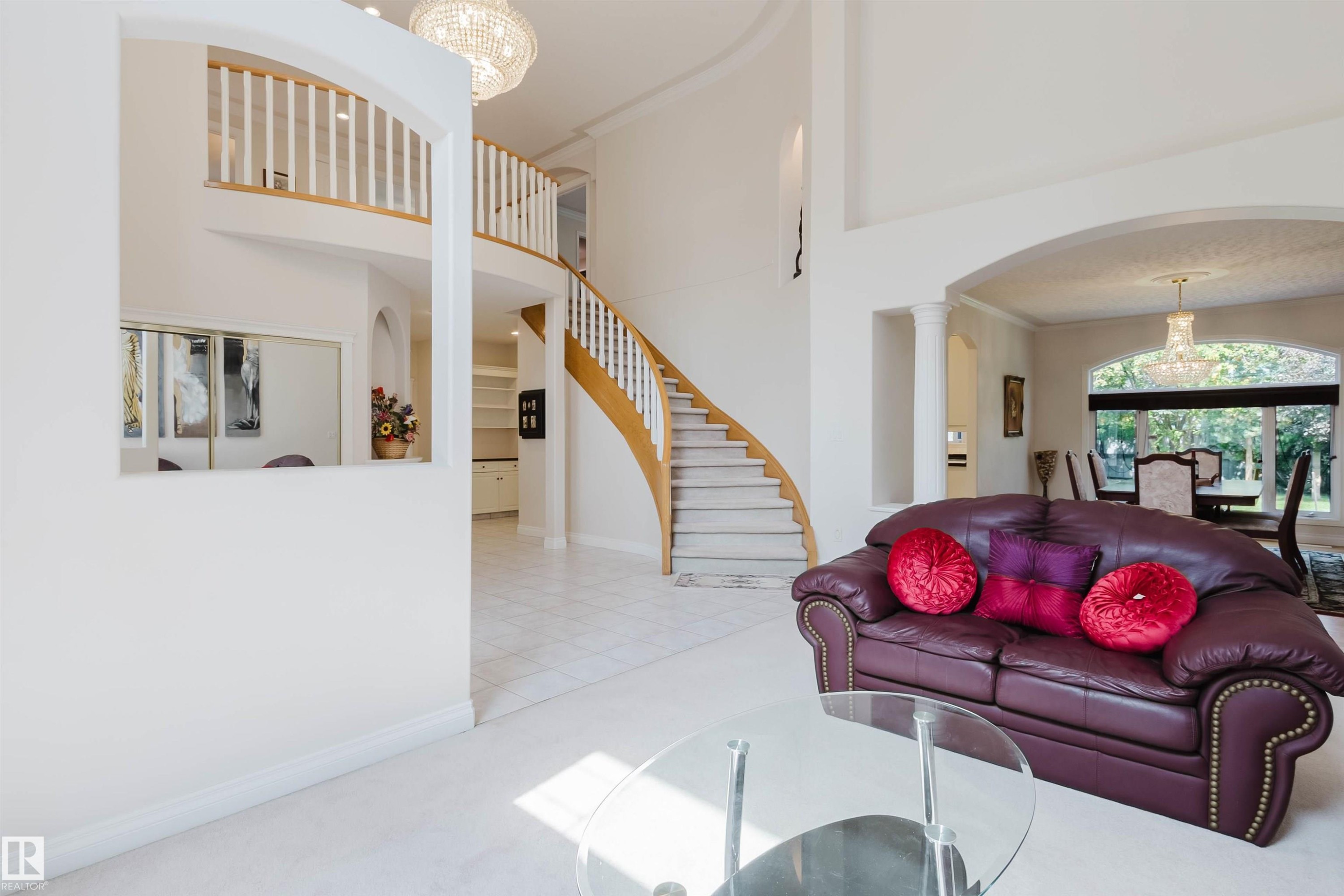 Grand foyer featuring a curved staircase with natural wood railings and white balusters - 928 Heacock Road Nw, Edmonton, AB - Indoor Photo Showing Living Room