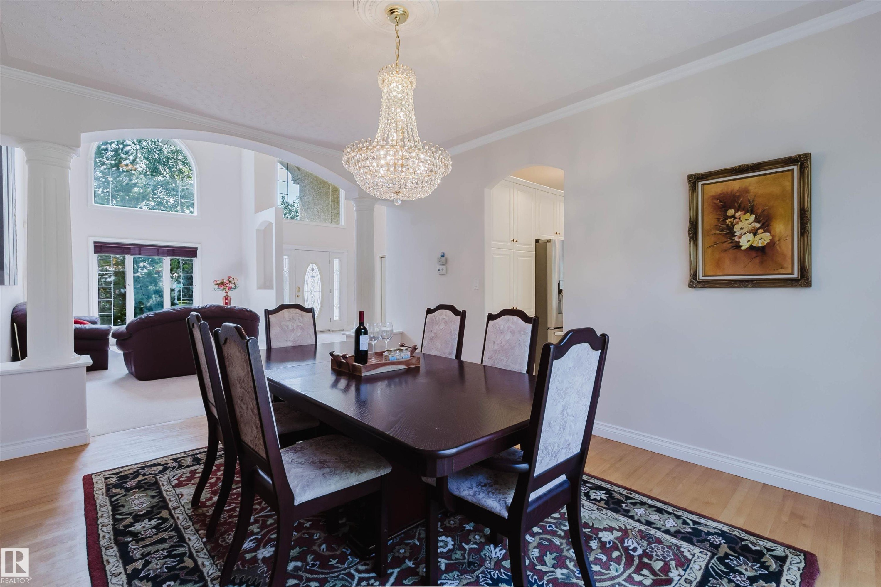 Formal dining space featuring a prominent crystal chandelier, light wood-finish flooring, and crown molding - 928 Heacock Road Nw, Edmonton, AB - Indoor Photo Showing Dining Room