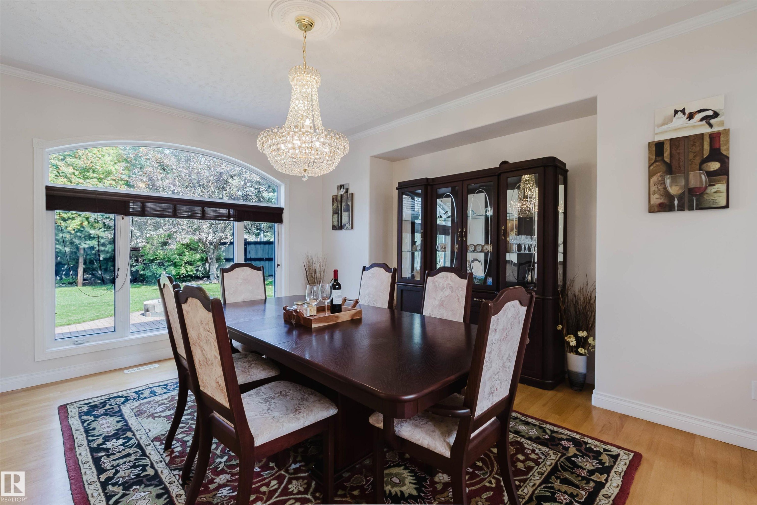 Arch-top window with backyard views, hardwood-finish flooring, and crown molding - 928 Heacock Road Nw, Edmonton, AB - Indoor Photo Showing Dining Room