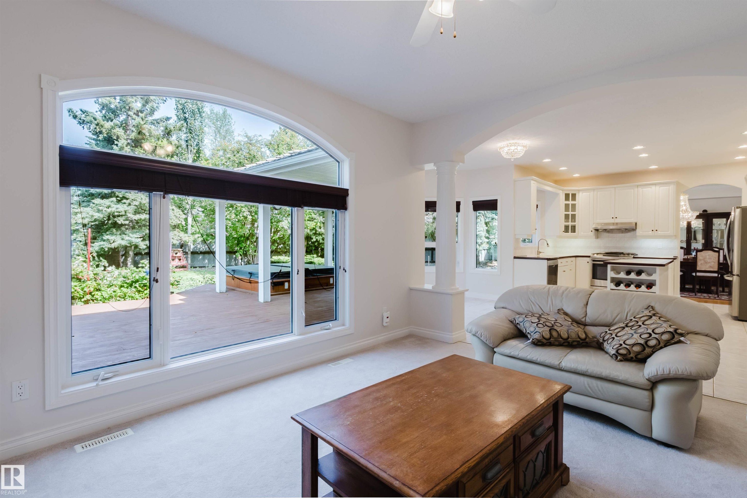 Arched window overlooking a wooden deck with an outdoor spa - 928 Heacock Road Nw, Edmonton, AB - Indoor Photo Showing Living Room