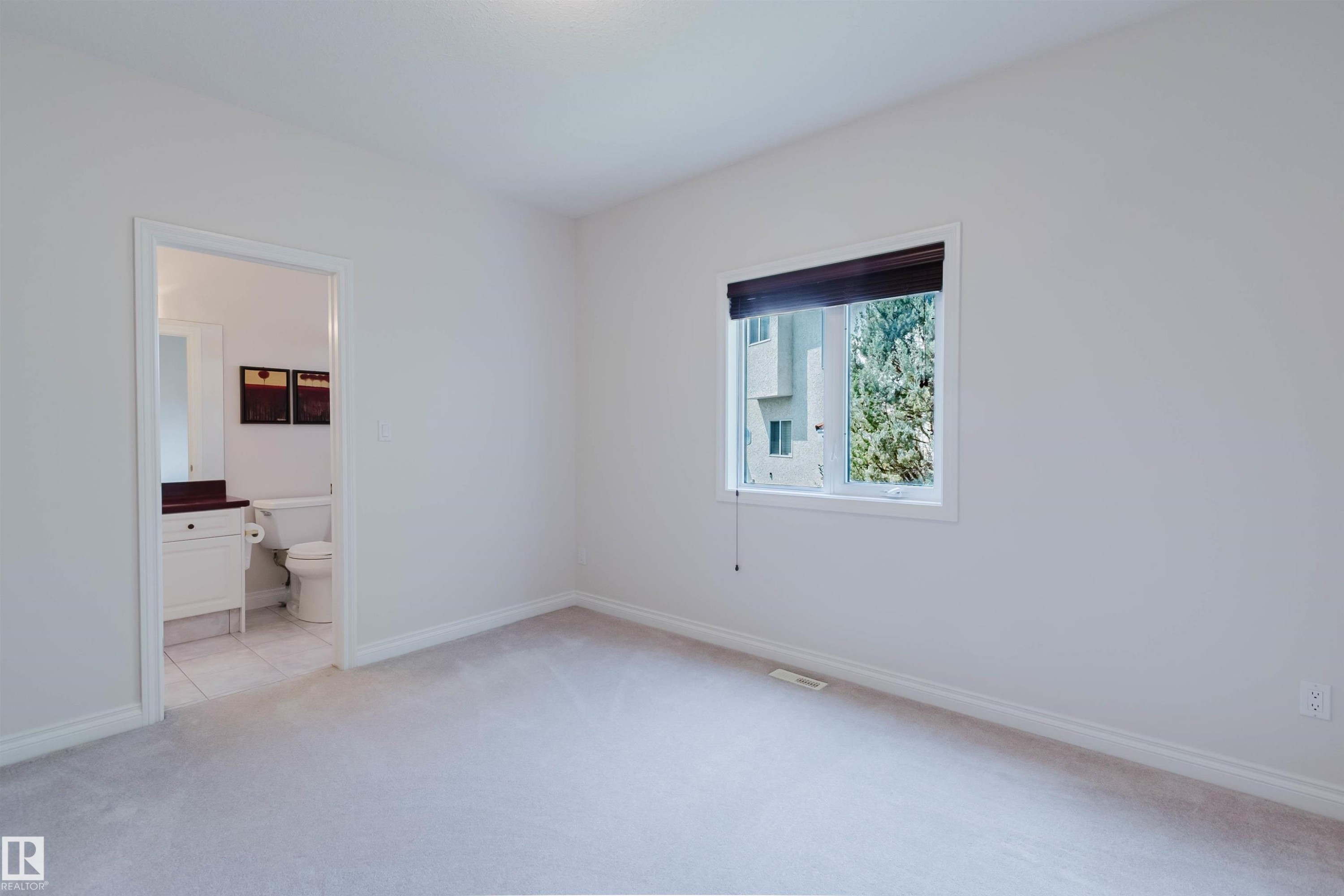 Carpeted room featuring a single window with a dark roller shade, white baseboards, and neutral wall paint - 928 Heacock Road Nw, Edmonton, AB - Indoor Photo Showing Other Room