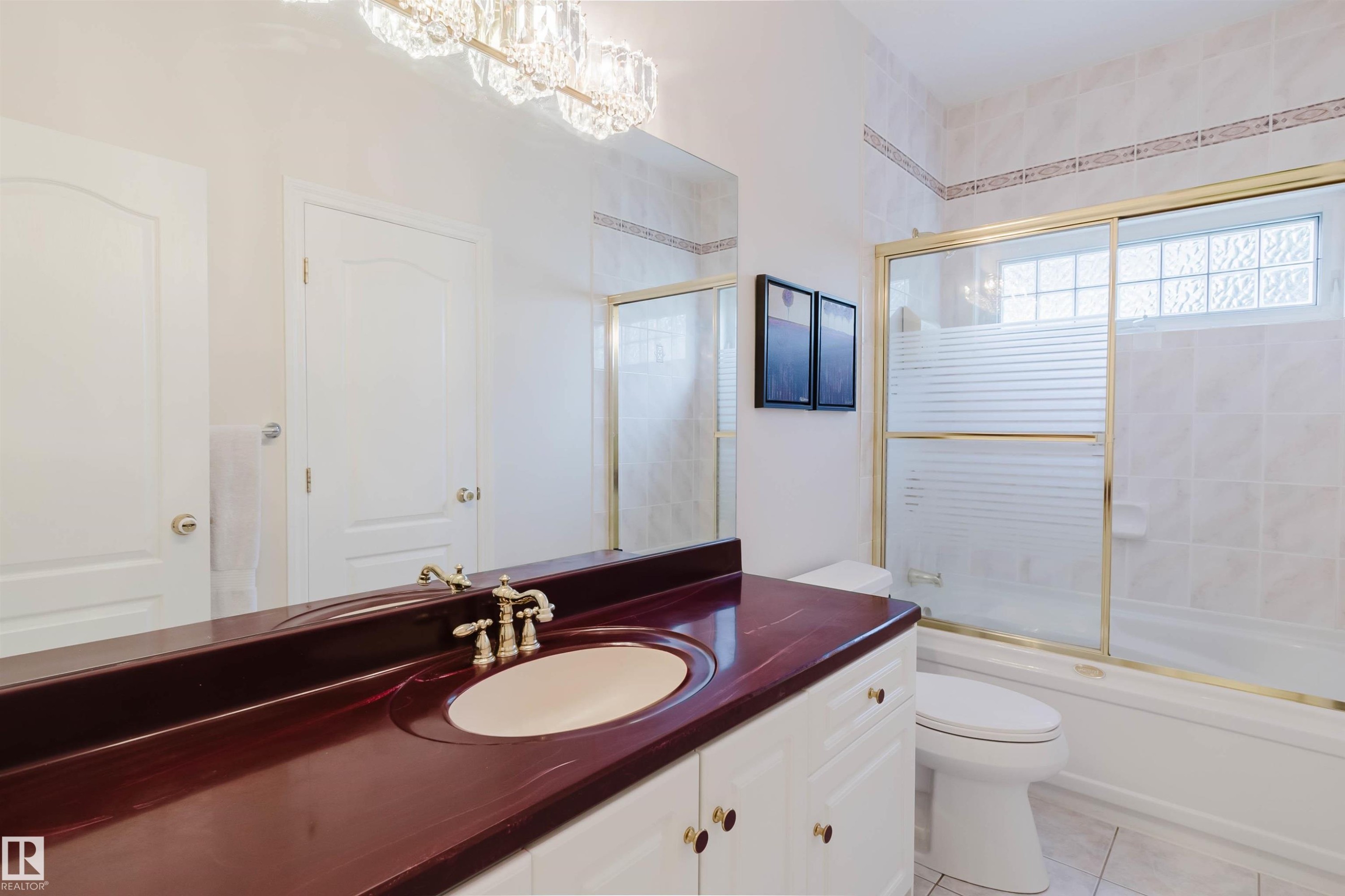 Bathroom featuring a white vanity with a deep red countertop, a drop-in sink, and a gold-framed shower/tub combination with sliding glass doors - 928 Heacock Road Nw, Edmonton, AB - Indoor Photo Showing Bathroom