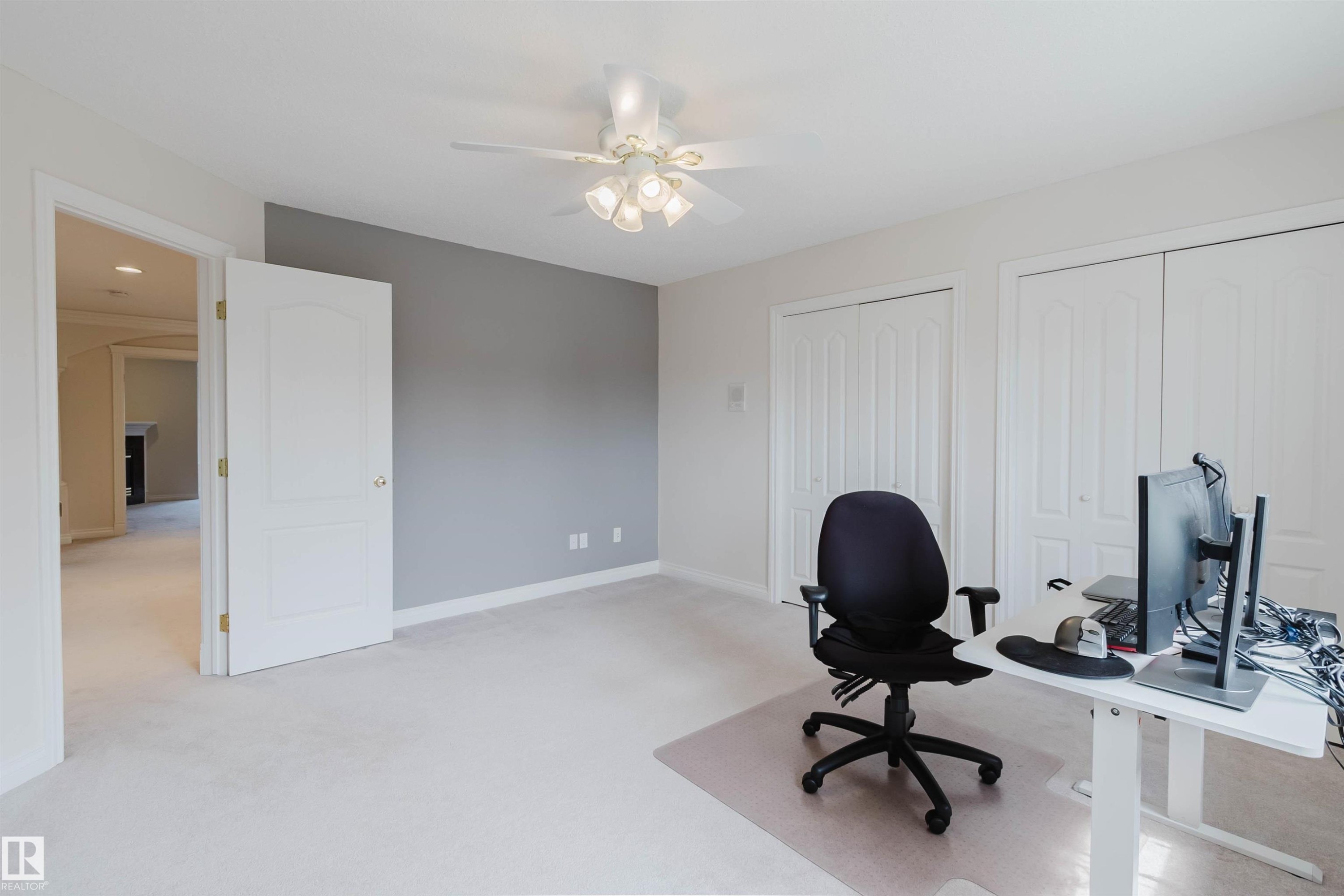 Spacious room with light-colored carpeting, a contrasting accent wall, two sets of bi-fold closet doors, a white ceiling fan with integrated lighting, and a white paneled door leading to another area - 928 Heacock Road Nw, Edmonton, AB - Indoor
