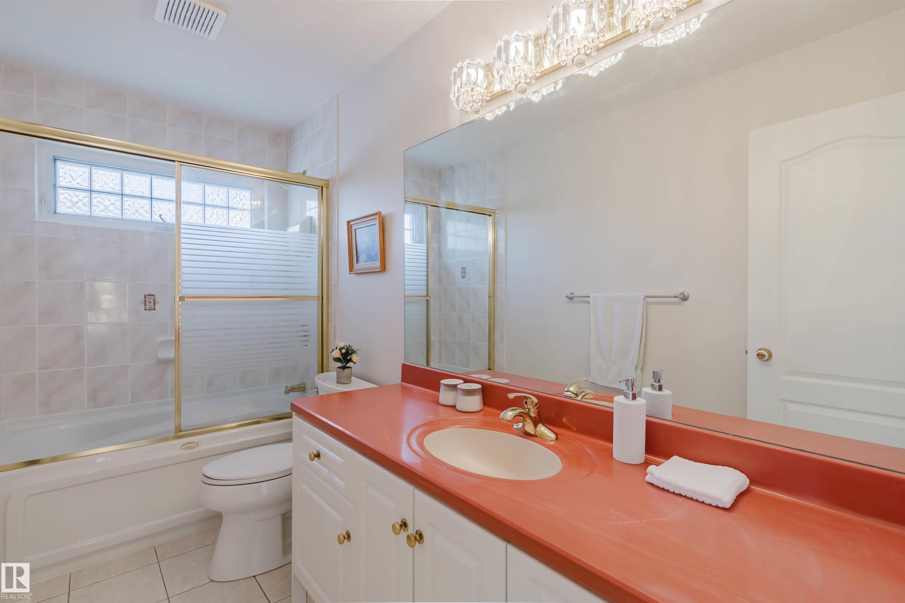 Bathroom featuring a vanity with a coral-hued countertop, an integrated sink, and gold-tone fixtures - 928 Heacock Road Nw, Edmonton, AB - Indoor Photo Showing Bathroom