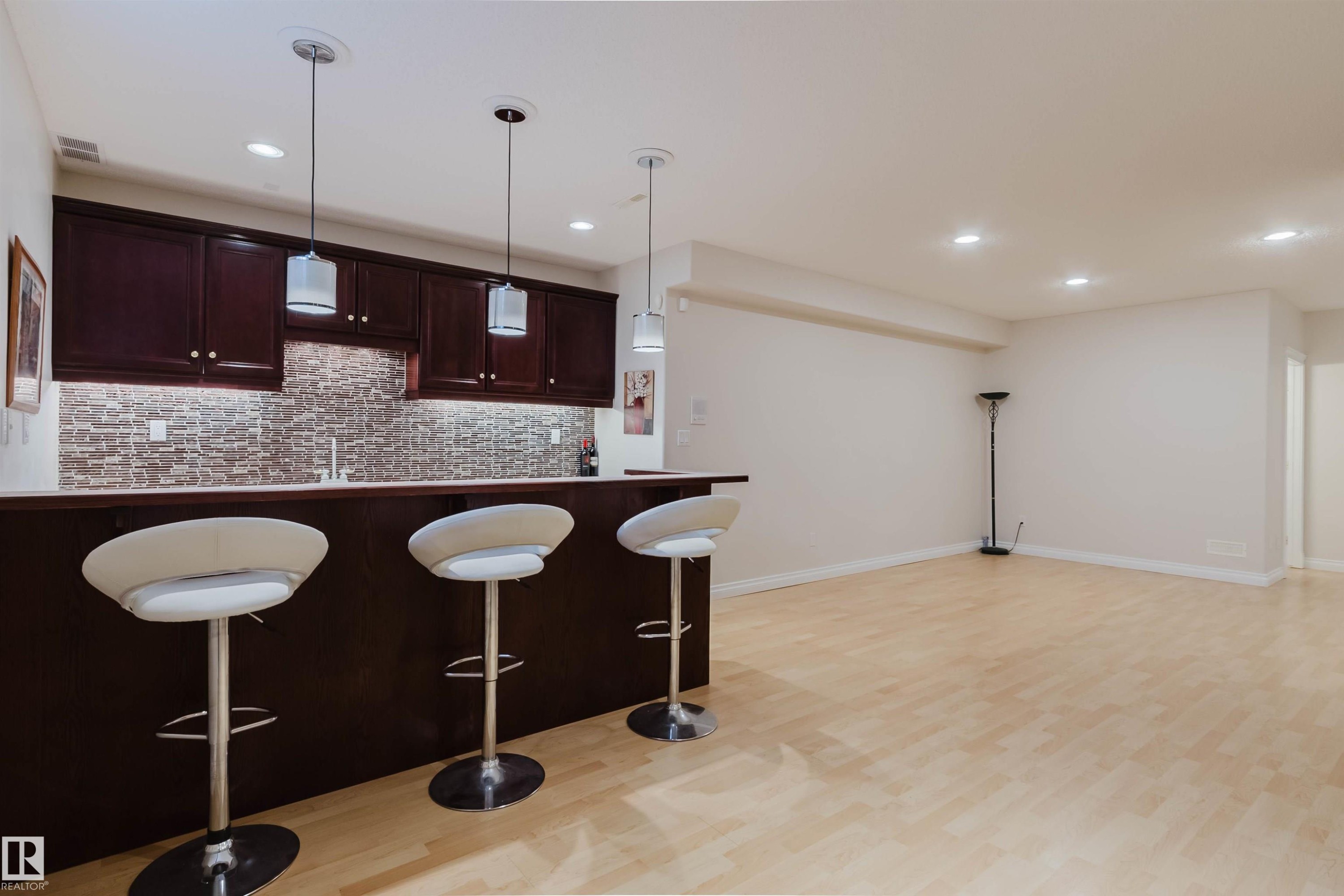 Entertainment space featuring a wet bar with dark wood cabinetry, a mosaic tile backsplash, and a light-toned countertop - 928 Heacock Road Nw, Edmonton, AB - Indoor Photo Showing Kitchen
