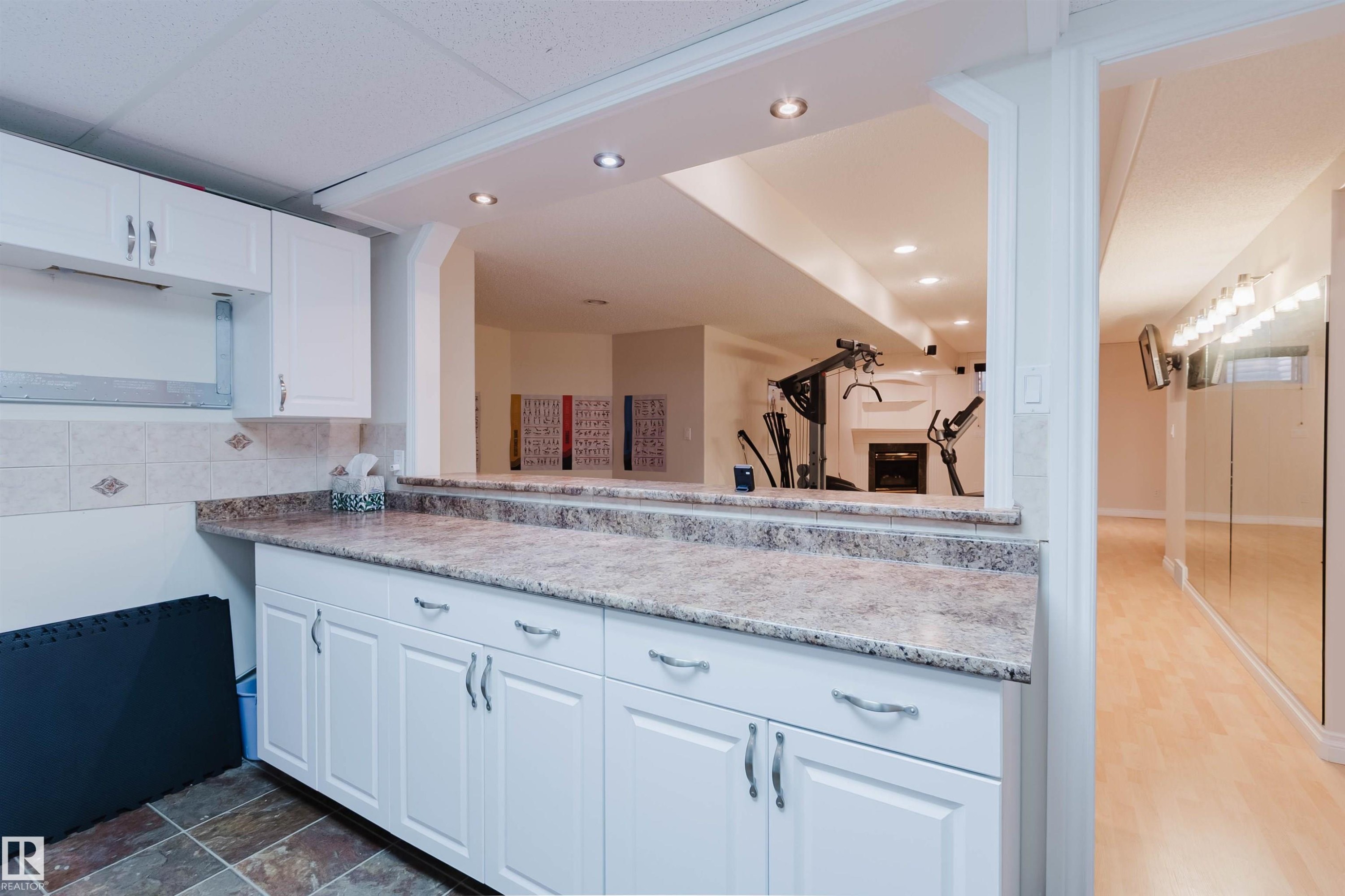 White cabinetry with chrome hardware, an expansive countertop, and tile backsplash - 928 Heacock Road Nw, Edmonton, AB - Indoor