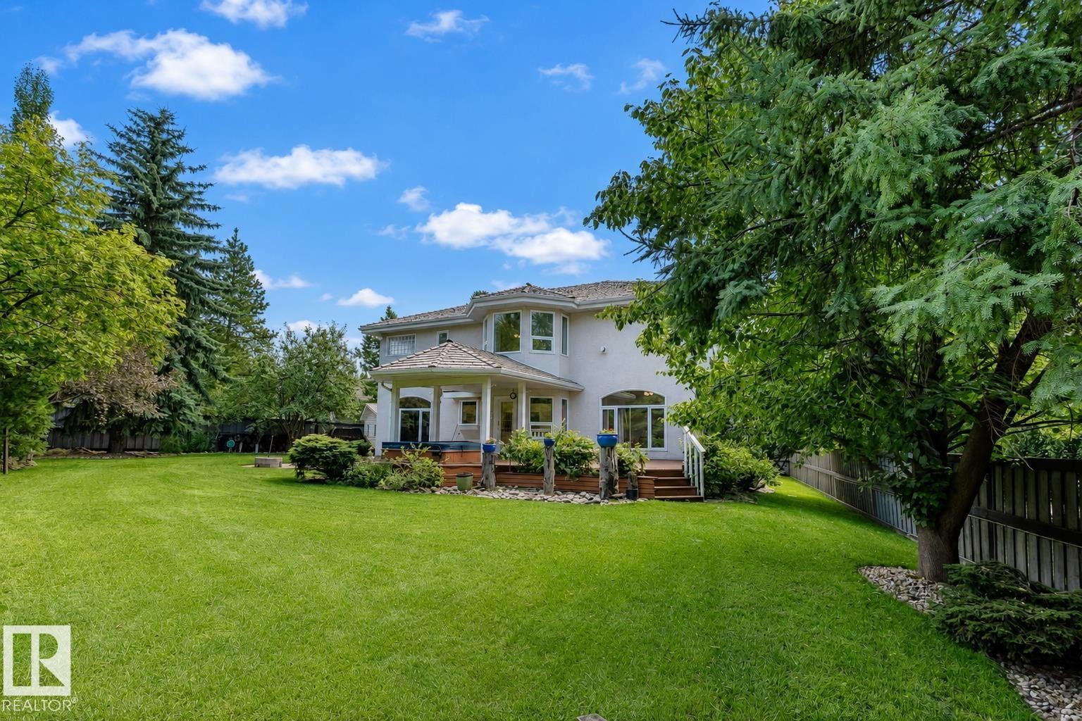 Expansive rear yard featuring a large lawn area, mature trees, and a multi-level deck with a covered patio - 928 Heacock Road Nw, Edmonton, AB - Outdoor With Deck Patio Veranda