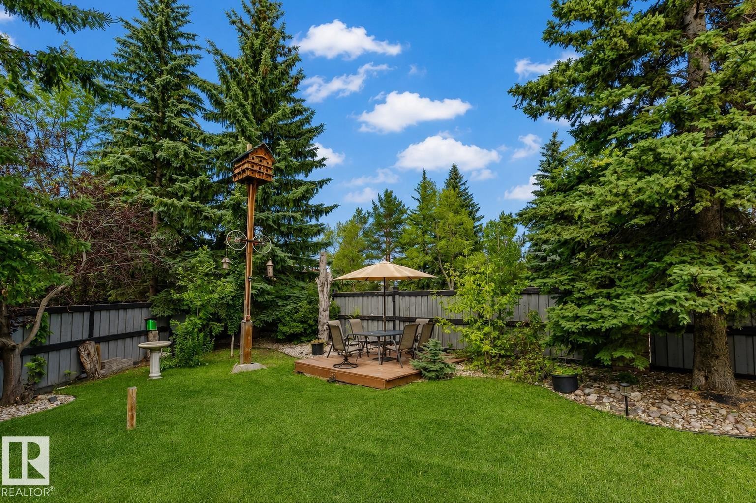 Expansive backyard featuring a manicured lawn, established perimeter fencing, and mature evergreen trees - 928 Heacock Road Nw, Edmonton, AB - Outdoor With Backyard
