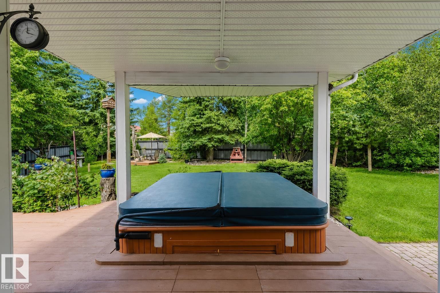 Covered outdoor patio featuring a hot tub with wood-finish siding, composite decking, and a ceiling fan - 928 Heacock Road Nw, Edmonton, AB - Outdoor With Deck Patio Veranda With Exterior