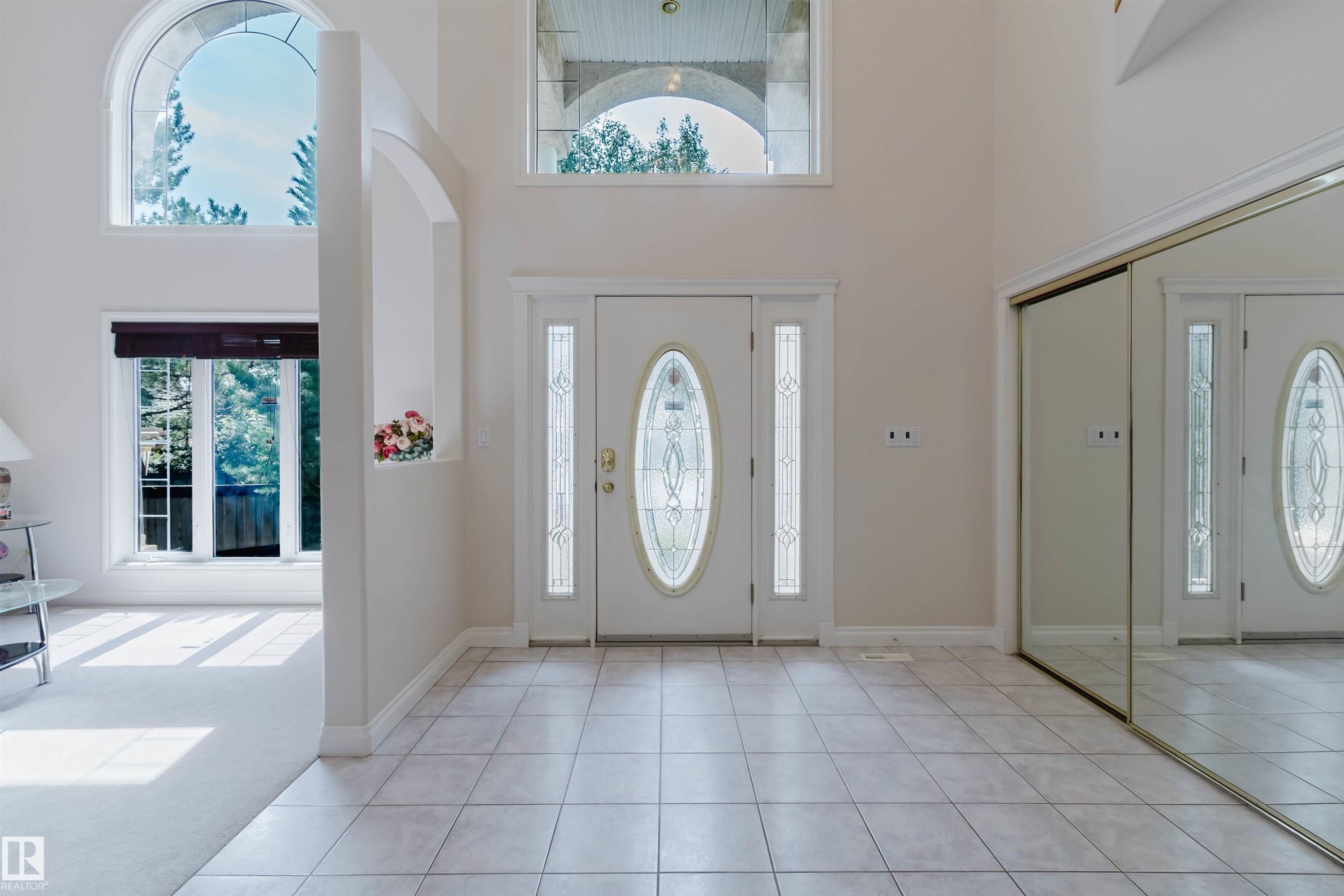 Grand entryway featuring a decorative glass front door with sidelights, a large mirrored closet, and tile flooring - 928 Heacock Road Nw, Edmonton, AB - Indoor Photo Showing Other Room
