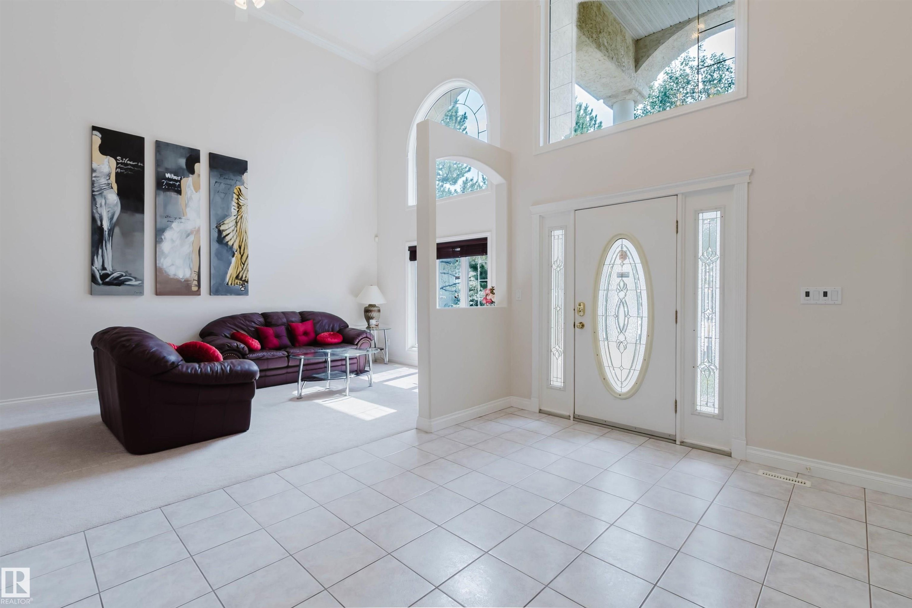 Two-story foyer featuring large format tile flooring, a decorative glass entry door with sidelights, and an arched transom window - 928 Heacock Road Nw, Edmonton, AB - Indoor Photo Showing Other Room