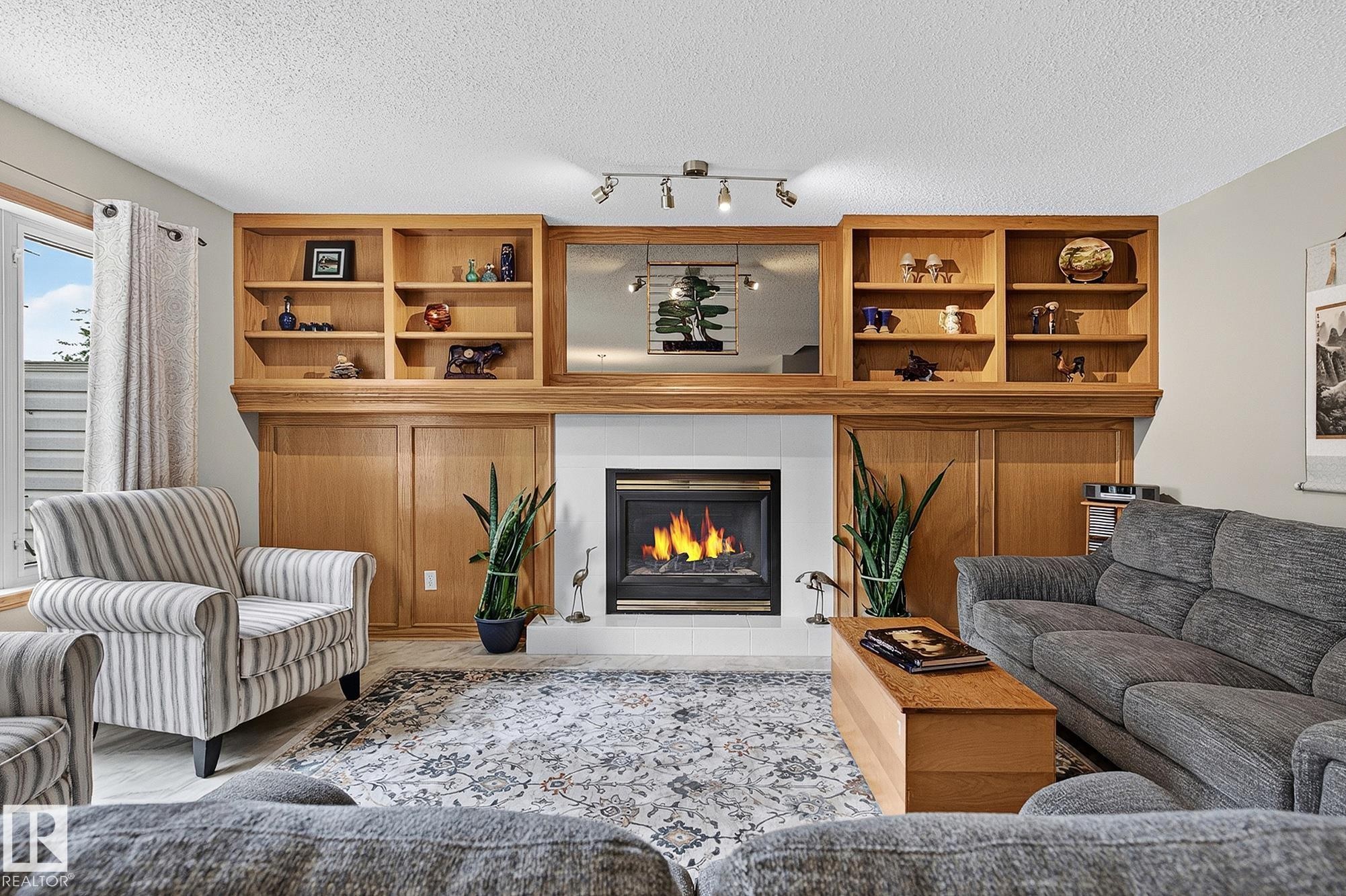 Built-in oak cabinetry with open shelving and closed storage flanks a gas fireplace - 385 Meadowview Terrace, Sherwood Park, AB - Indoor Photo Showing Living Room With Fireplace
