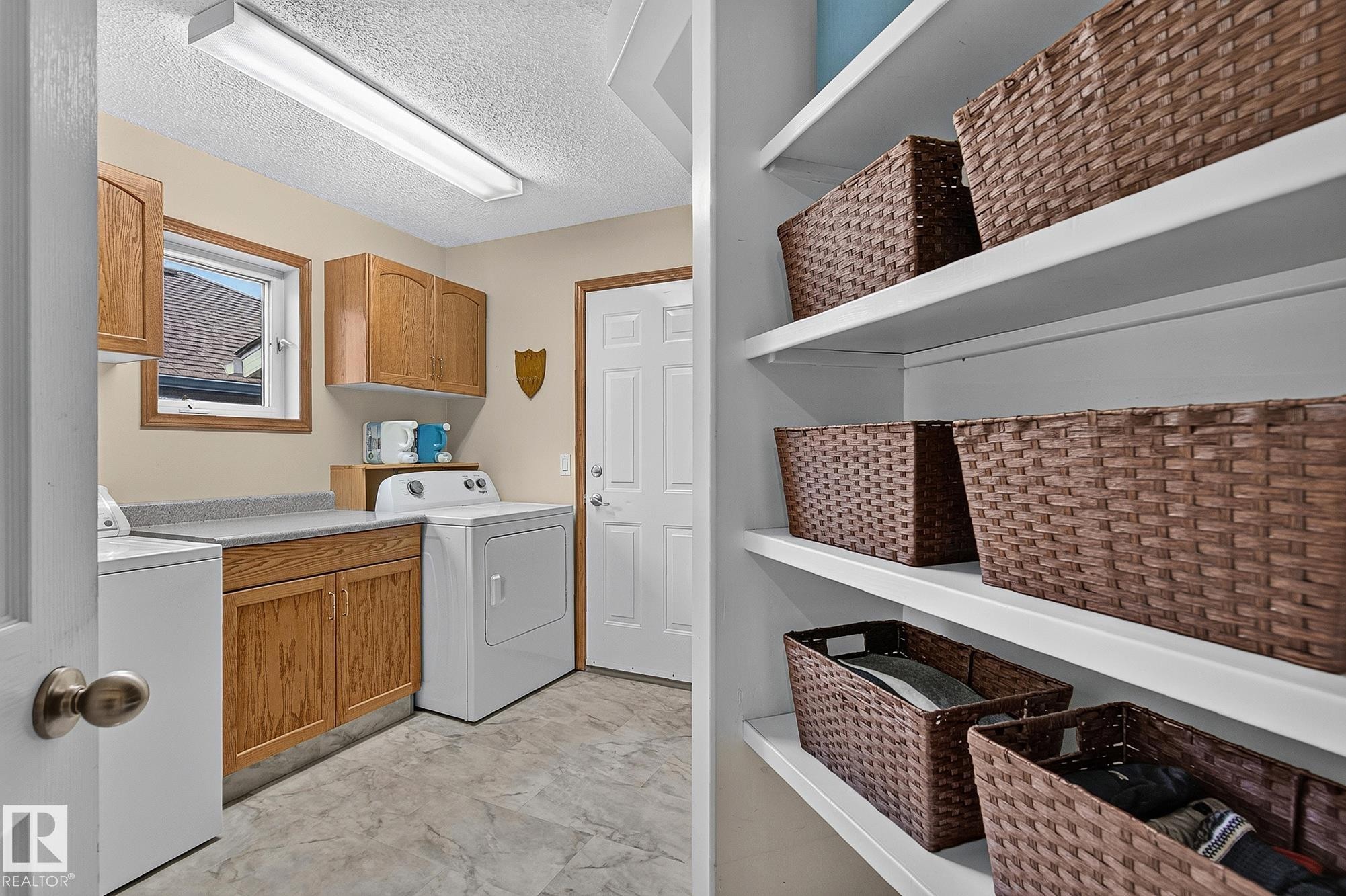 Garage entry includes the laundry room featuring wood cabinetry, a laminate countertop, and a window for natural light - 385 Meadowview Terrace, Sherwood Park, AB - Indoor Photo Showing Laundry Room