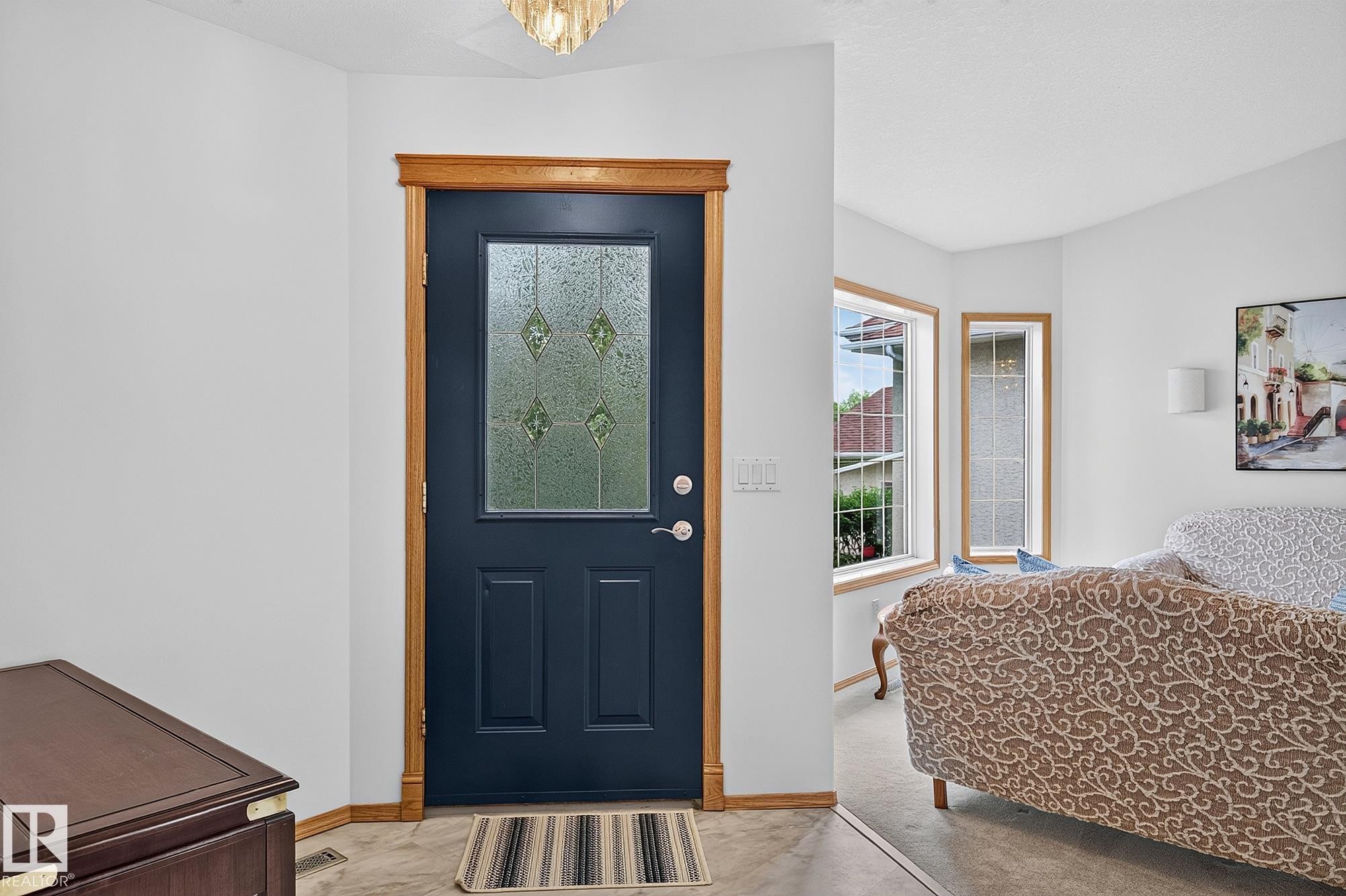 Entry door with decorative glass panel and light wood-finish trim, complemented by a light-colored ceiling fixture - 385 Meadowview Terrace, Sherwood Park, AB - Indoor