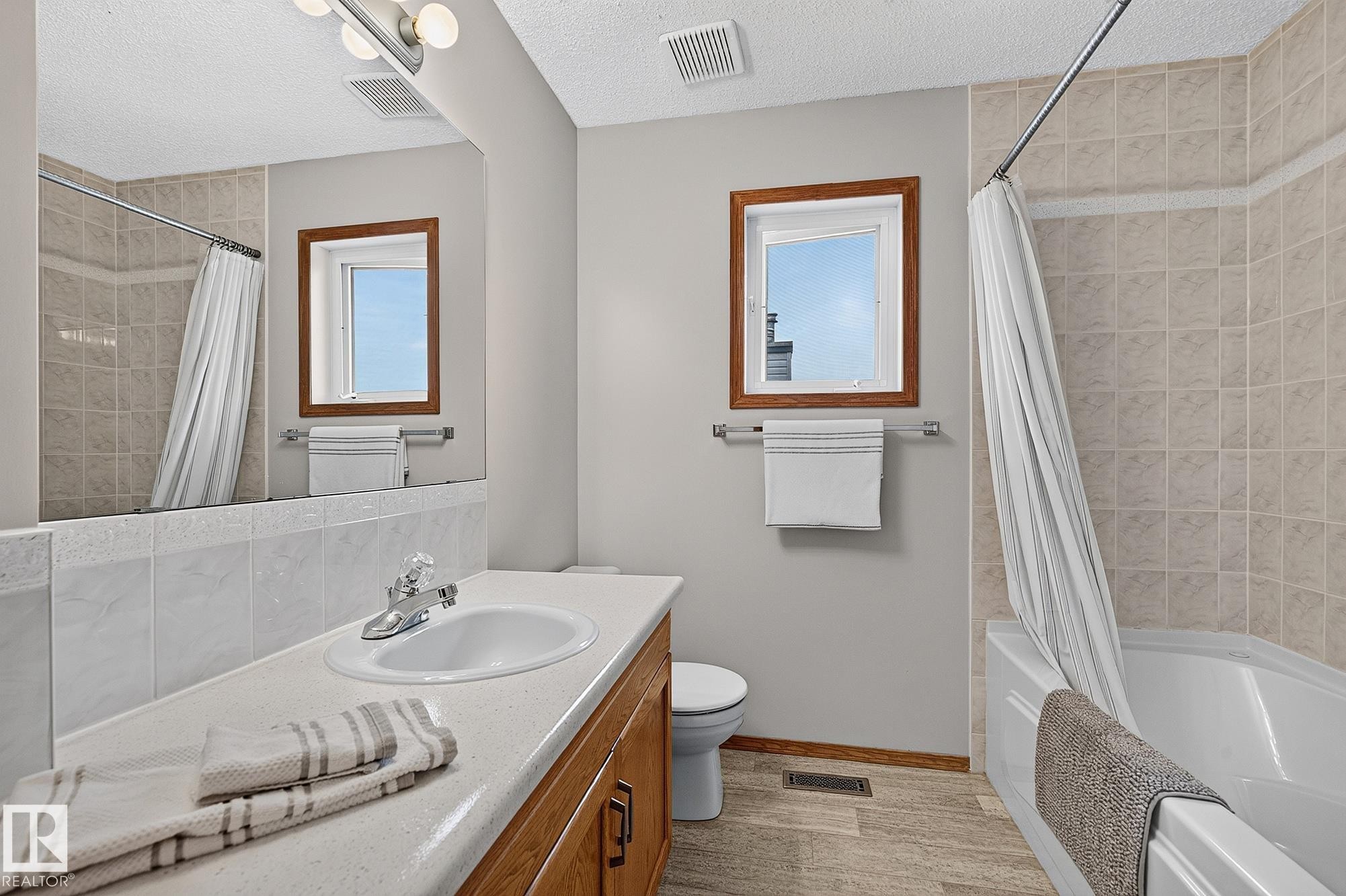 Main upstairs bathroom vanity with integrated sink, chrome faucet, and wood-finish cabinetry - 385 Meadowview Terrace, Sherwood Park, AB - Indoor Photo Showing Bathroom