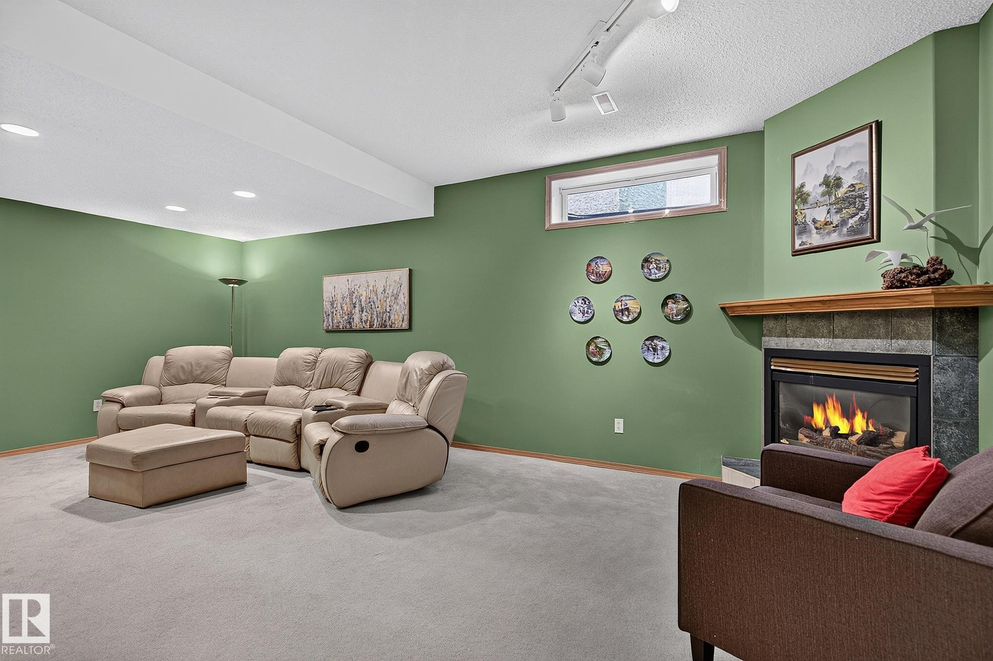 Carpeted room featuring a gas fireplace with a wood mantle, recessed lighting, and a horizontal window - 385 Meadowview Terrace, Sherwood Park, AB - Indoor Photo Showing Basement With Fireplace