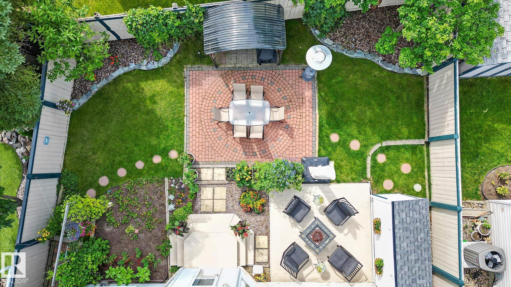 Aerial view of the expansive backyard featuring a red brick paver patio, a concrete patio, and a manicured lawn - 385 Meadowview Terrace, Sherwood Park, AB - Outdoor