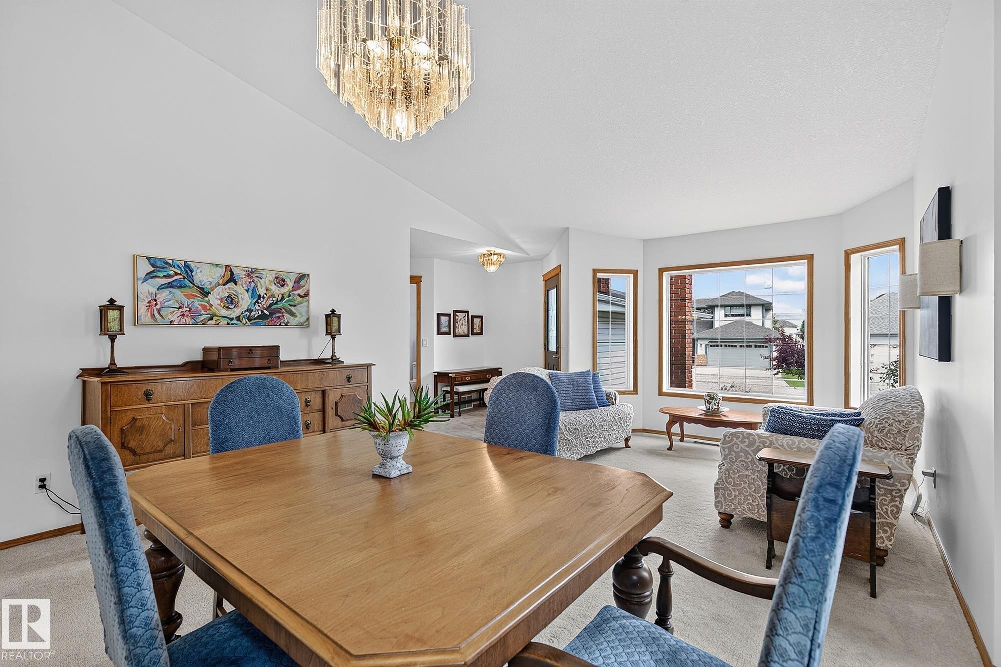 Spacious dining area featuring a tiered crystal chandelier, wood-finish flooring, and a large bay window - 385 Meadowview Terrace, Sherwood Park, AB - Indoor Photo Showing Dining Room