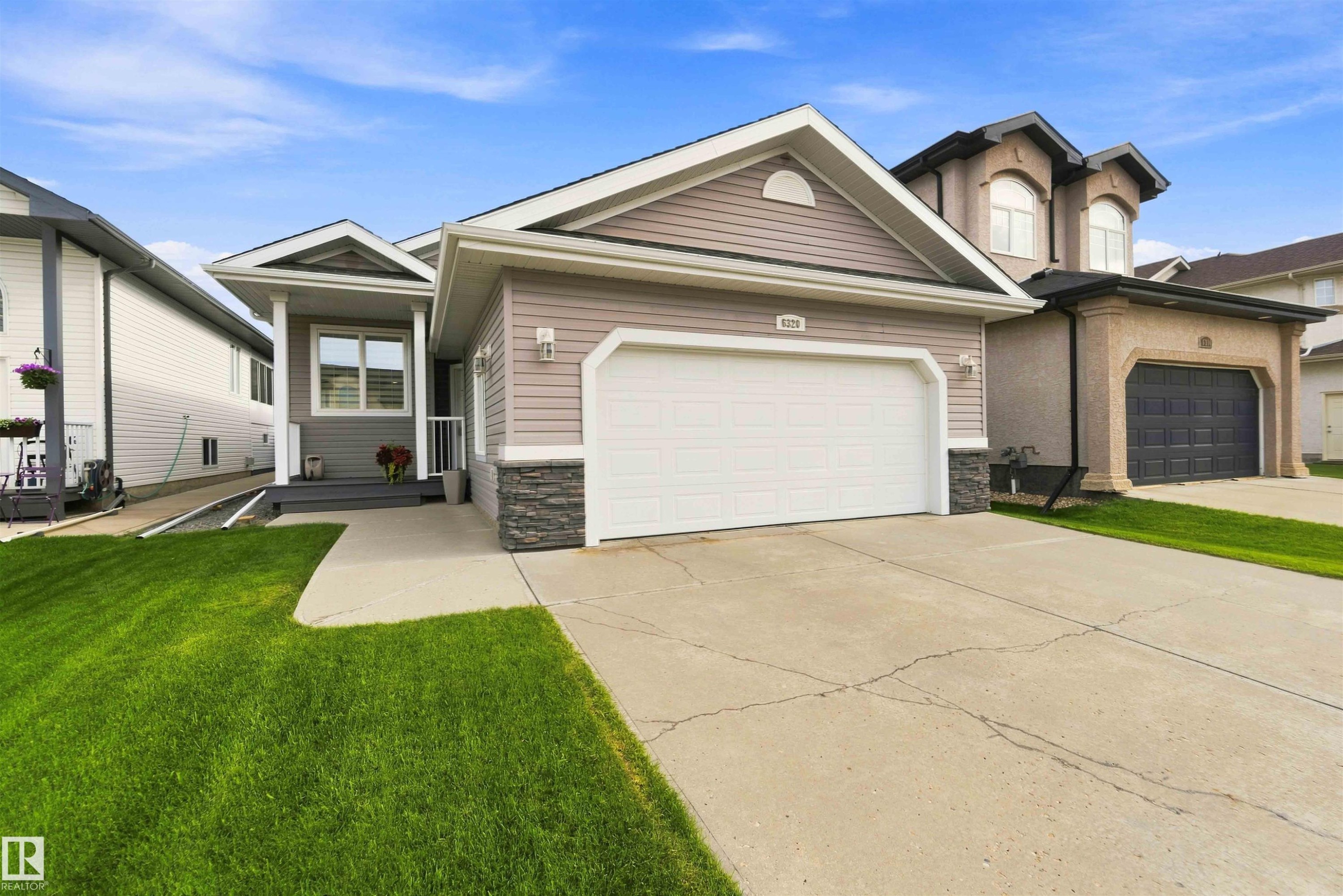 Exterior features include horizontal siding with stone accents, a prominent front garage, a covered entryway, and a concrete driveway - 6320 166 Avenue Nw, Edmonton, AB - Outdoor With Facade
