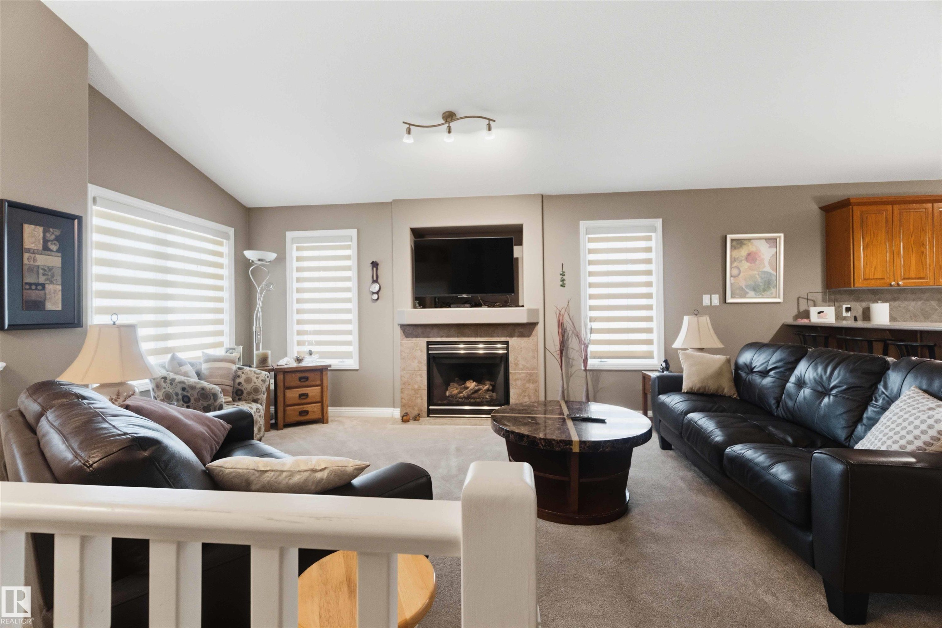 Living area featuring a vaulted ceiling and carpeted flooring - 6320 166 Avenue Nw, Edmonton, AB - Indoor Photo Showing Living Room With Fireplace