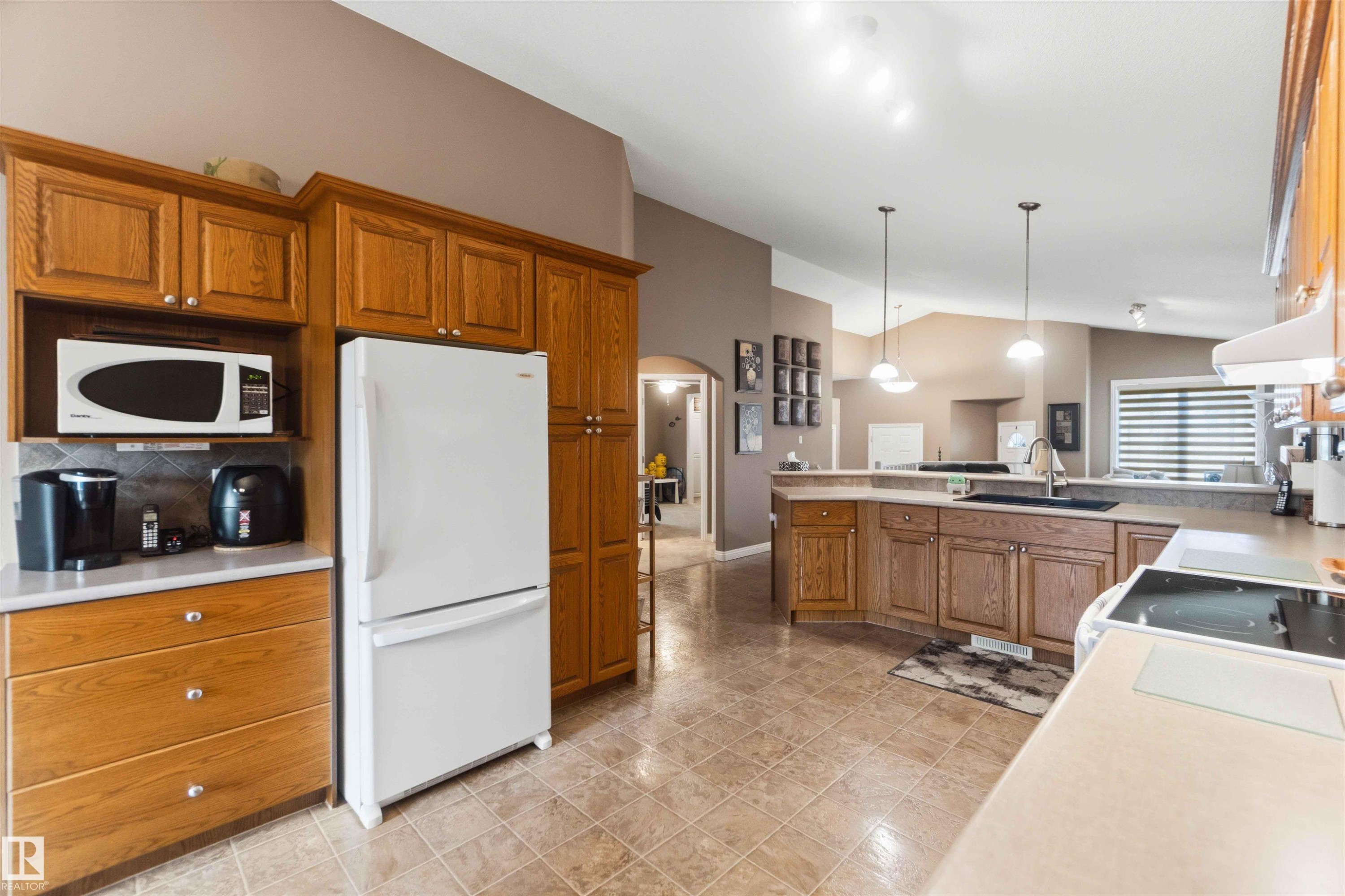 Kitchen featuring wood cabinetry, light-toned countertops, and tile flooring - 6320 166 Avenue Nw, Edmonton, AB - Indoor Photo Showing Kitchen