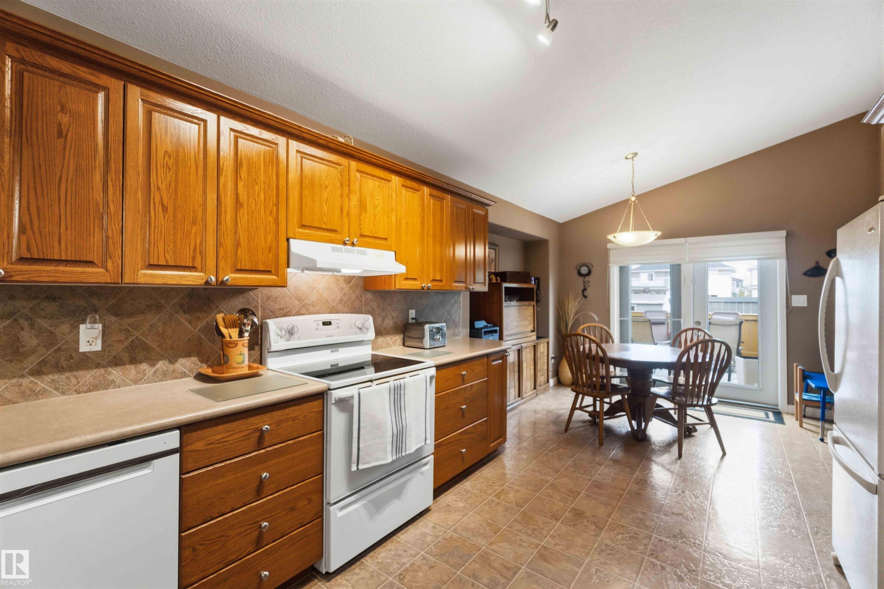 Kitchen featuring wood cabinetry, tiled flooring, and a vaulted ceiling - 6320 166 Avenue Nw, Edmonton, AB - Indoor Photo Showing Kitchen
